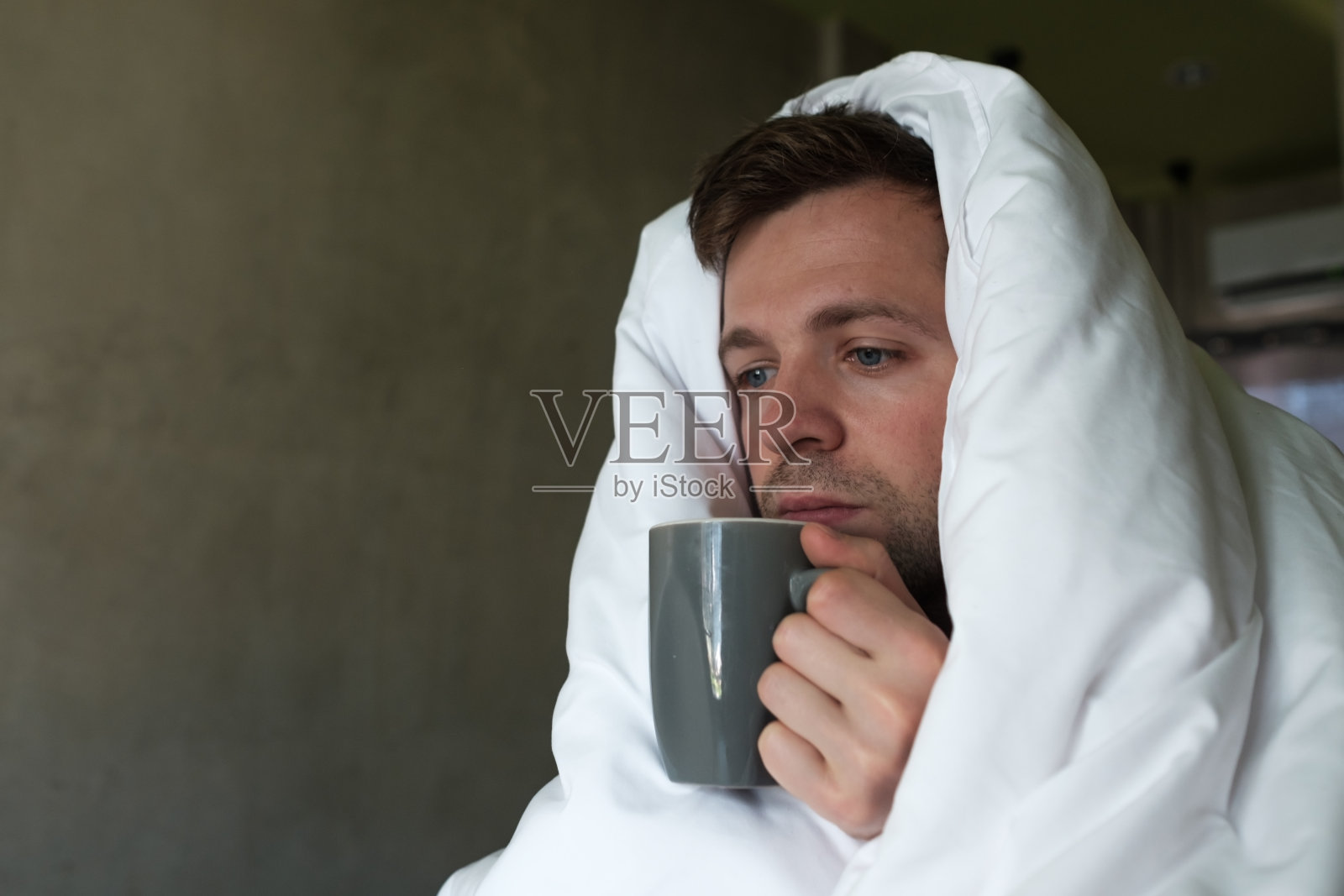 白人男性，因患流感而睡眠不足，躺在床上要求喝水或吃药照片摄影图片