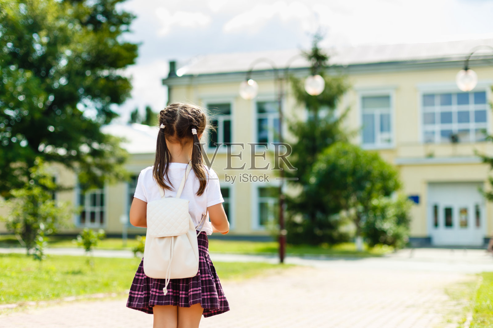 小女孩背着背包去上学。后视图照片摄影图片