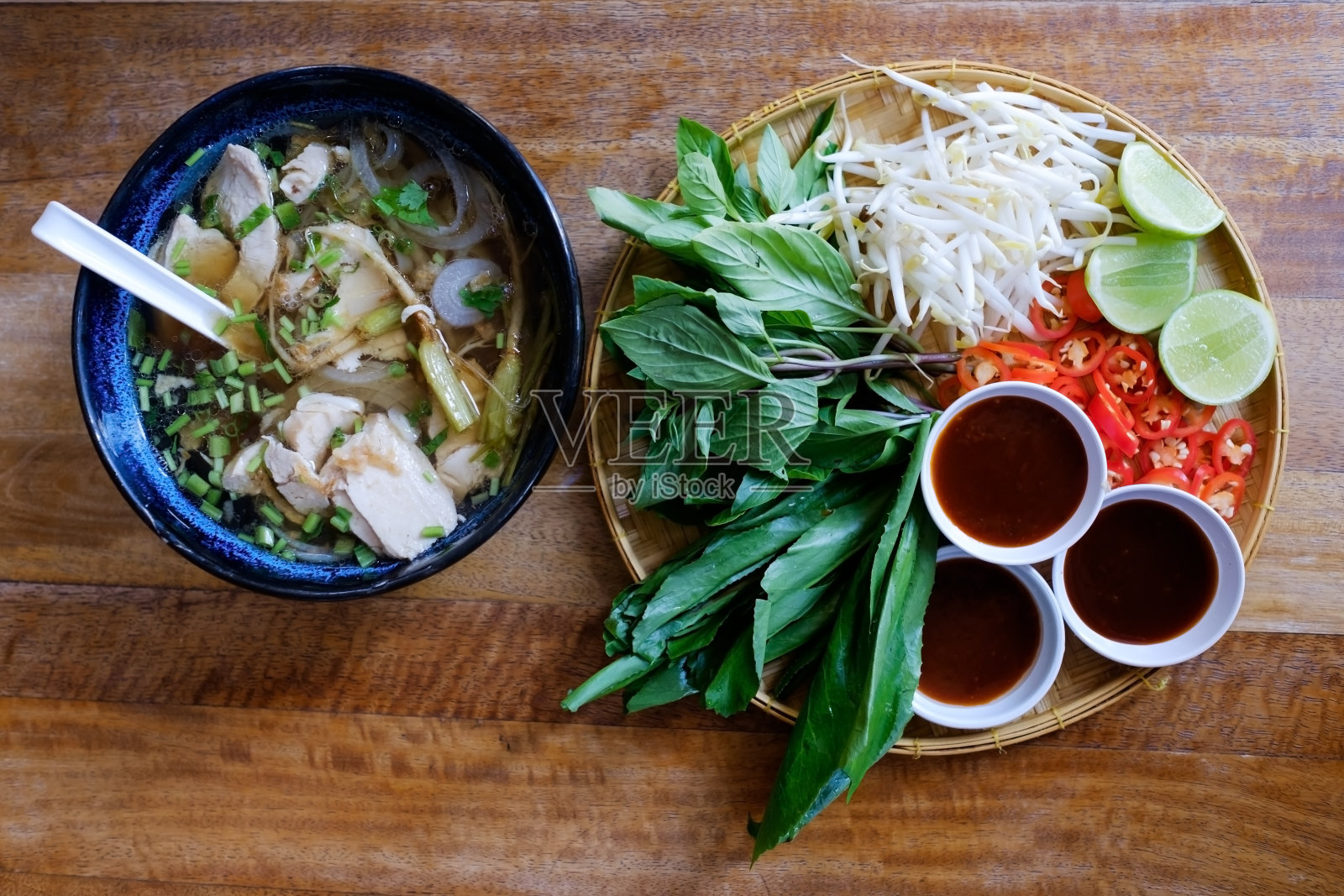 传统的越南菜。汤、面包卷和新鲜香草。木板表面上的盘子。照片摄影图片