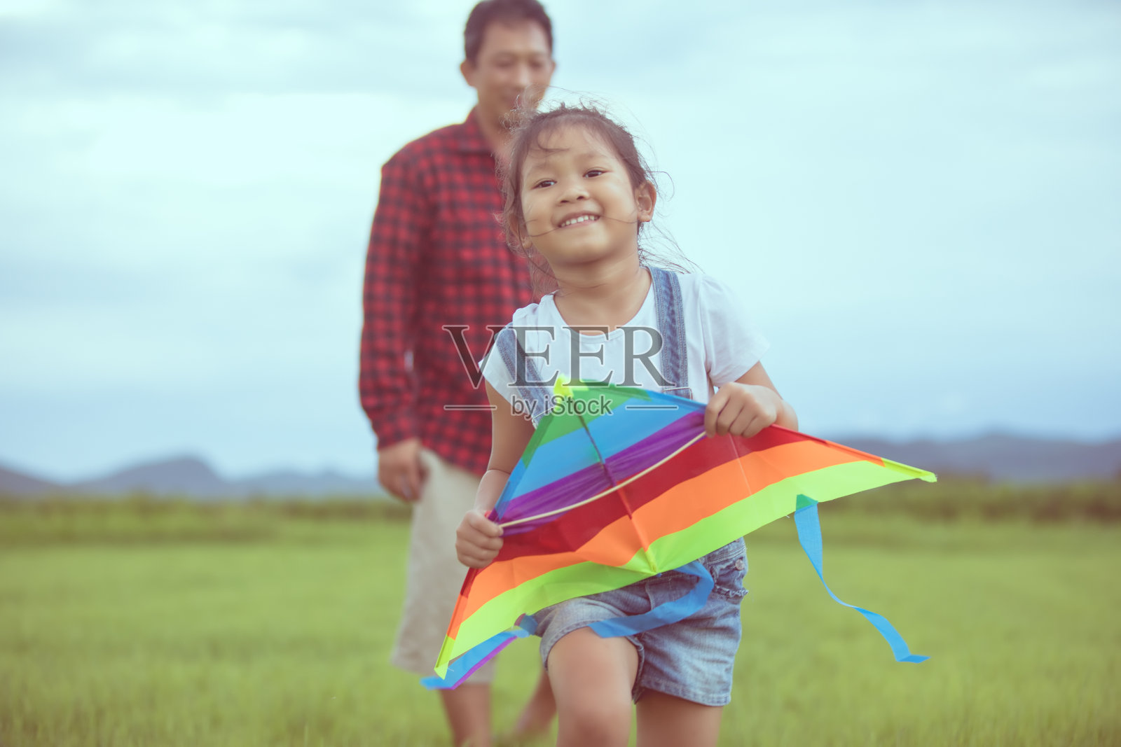 亚洲的孩子女孩和父亲与风筝跑和快乐的草地在夏季的自然照片摄影图片