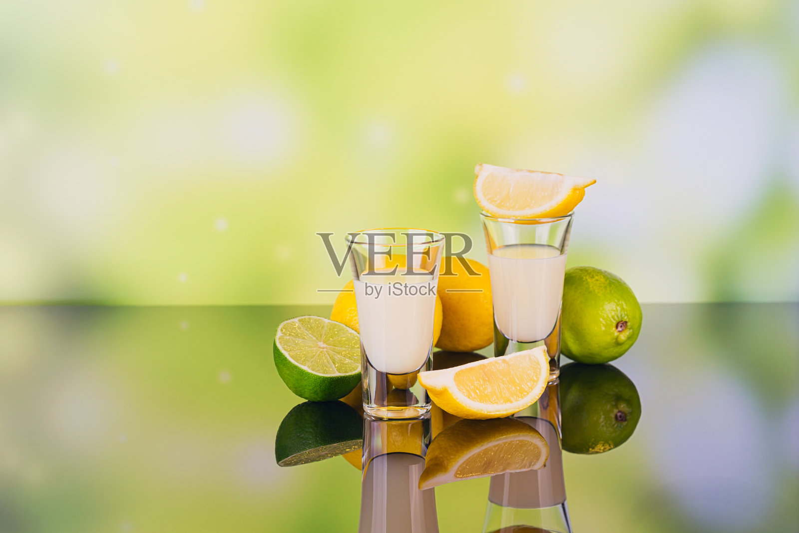 奶油利口酒与酸橙和柠檬在绿色的背景反射。照片摄影图片