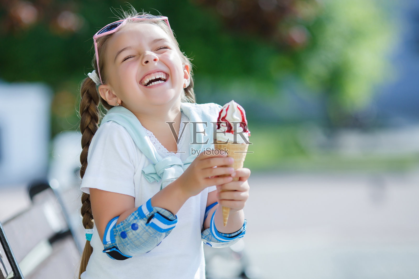 快乐的小女孩在公园里吃着甜筒冰淇淋照片摄影图片