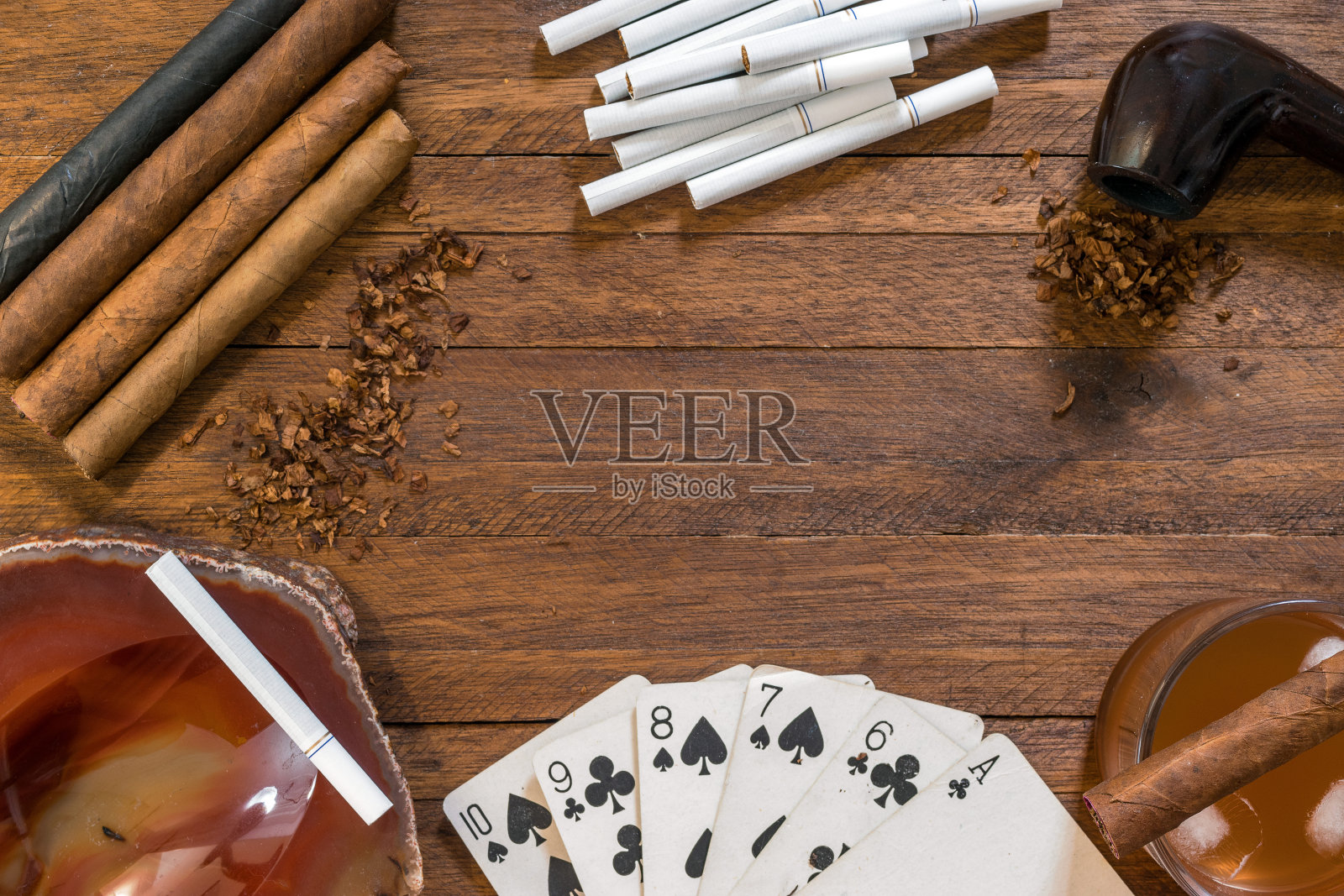 吸烟和烟草制品，雪茄，香烟和烟斗与烟草，上面的木制背景，与扑克牌，烟灰缸和酒精饮料照片摄影图片