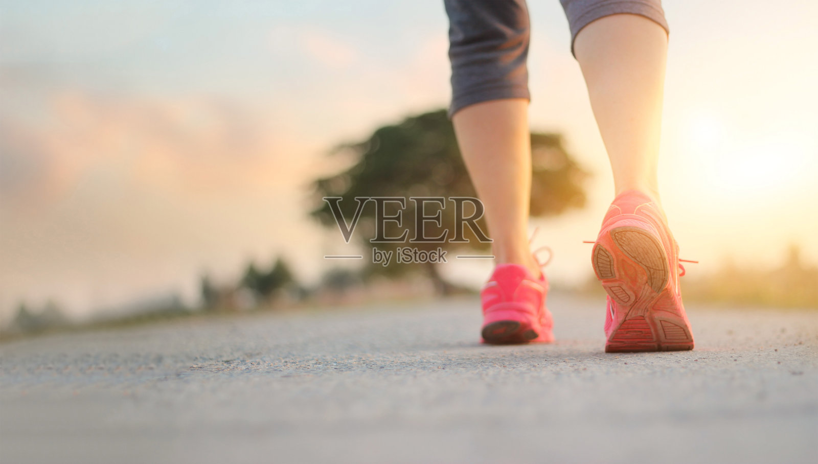女运动员在日落背景下的乡村道路上散步锻炼，健康和生活方式的概念照片摄影图片