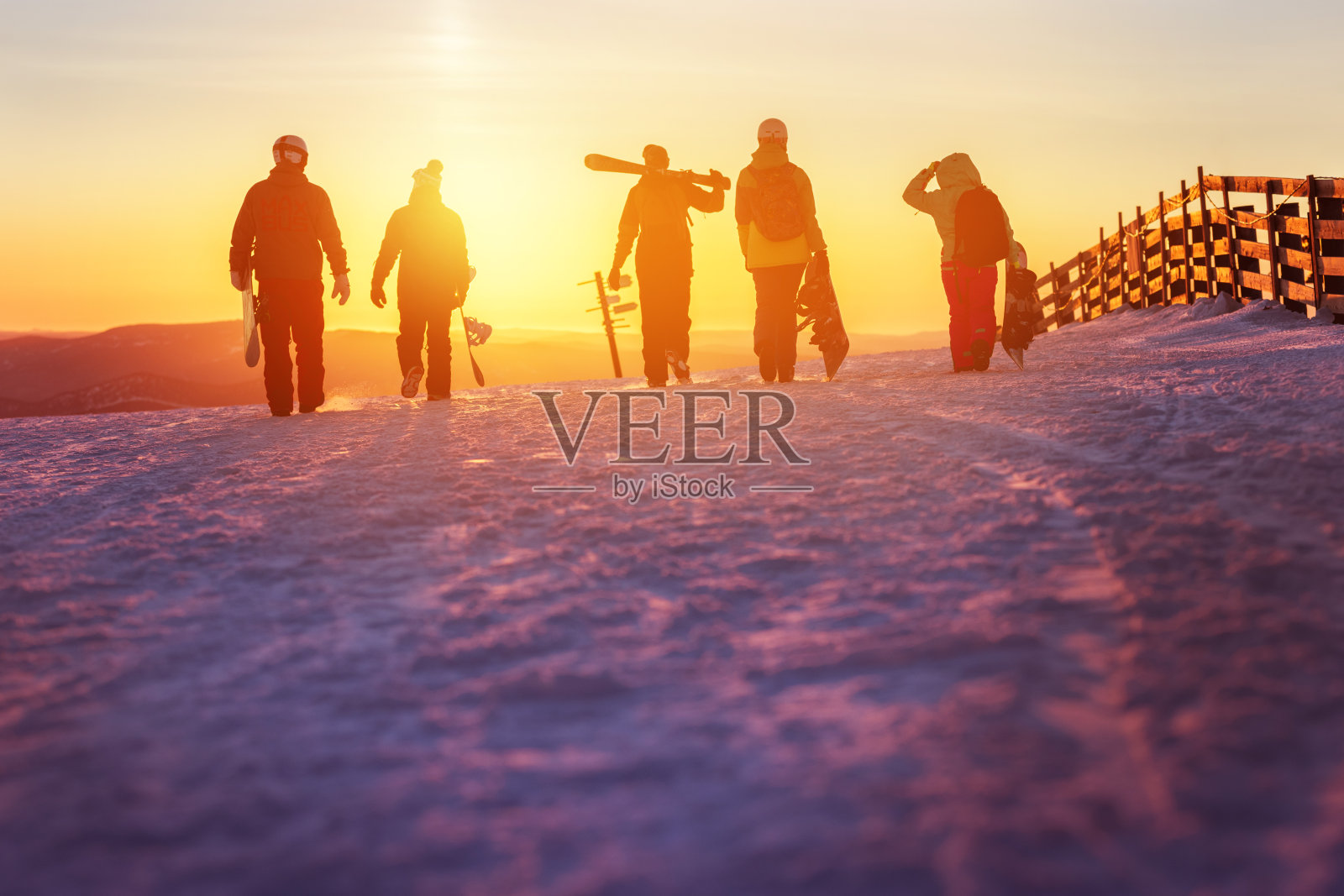 朋友们带着滑雪板和滑雪板在夕阳下散步照片摄影图片