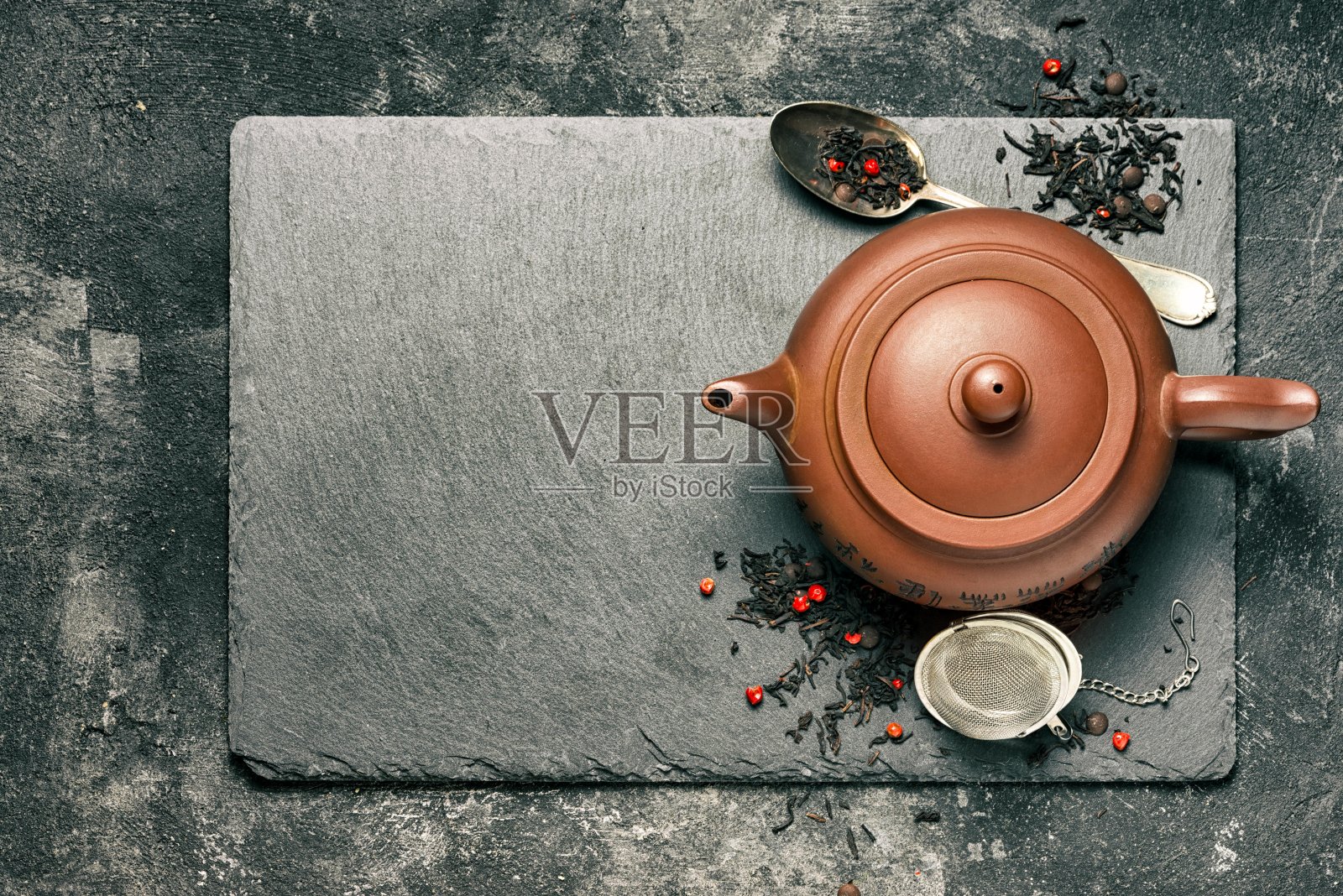 中国传统的红粘土茶壶和红茶冲泡的背景是一个黑色的石头托盘，俯视图在一个黑色的背景，壶的顶端朝向自由的空间供你的文字。照片摄影图片