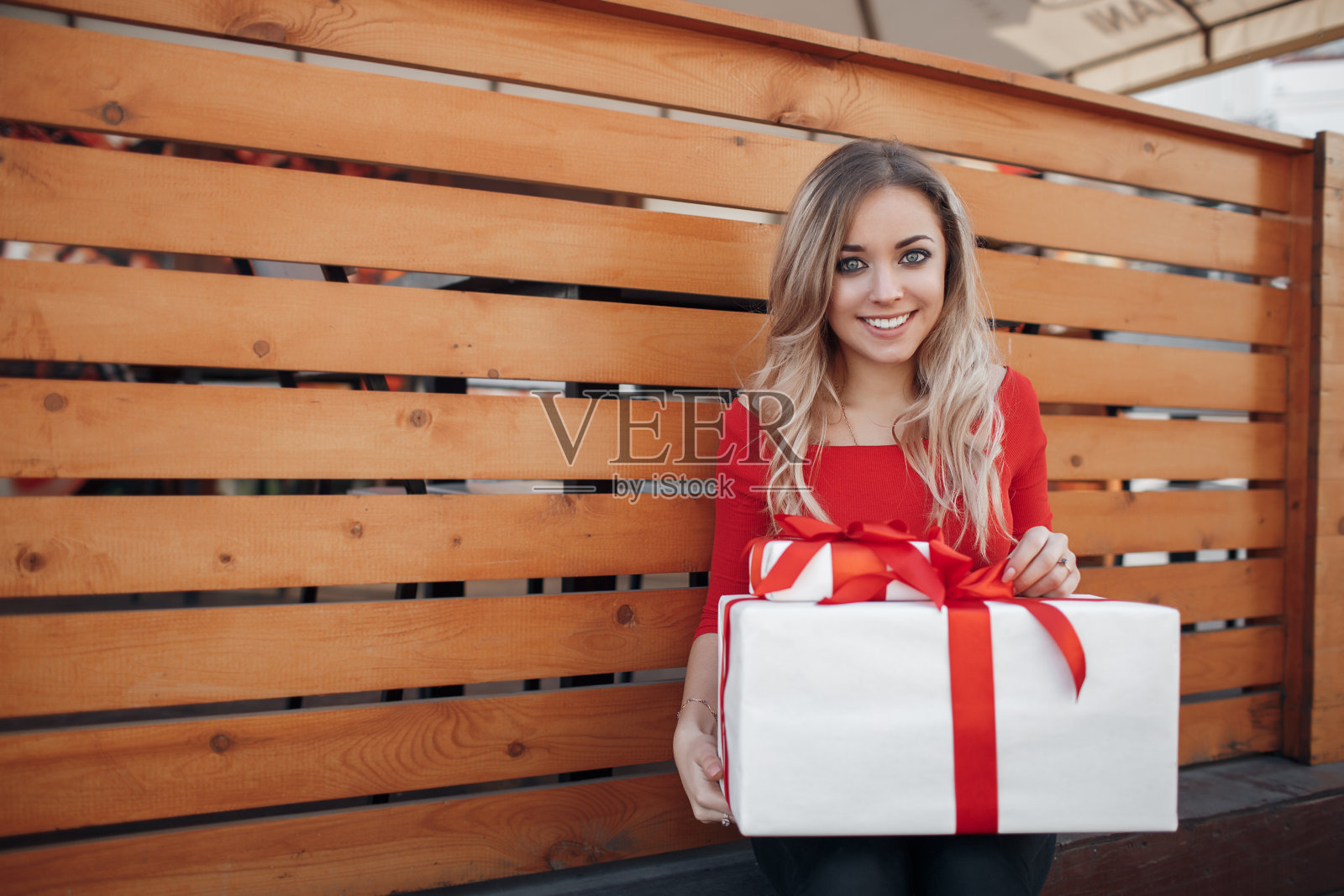 年轻漂亮的女人，手里拿着一个白色的礼盒，用红丝带系着照片摄影图片