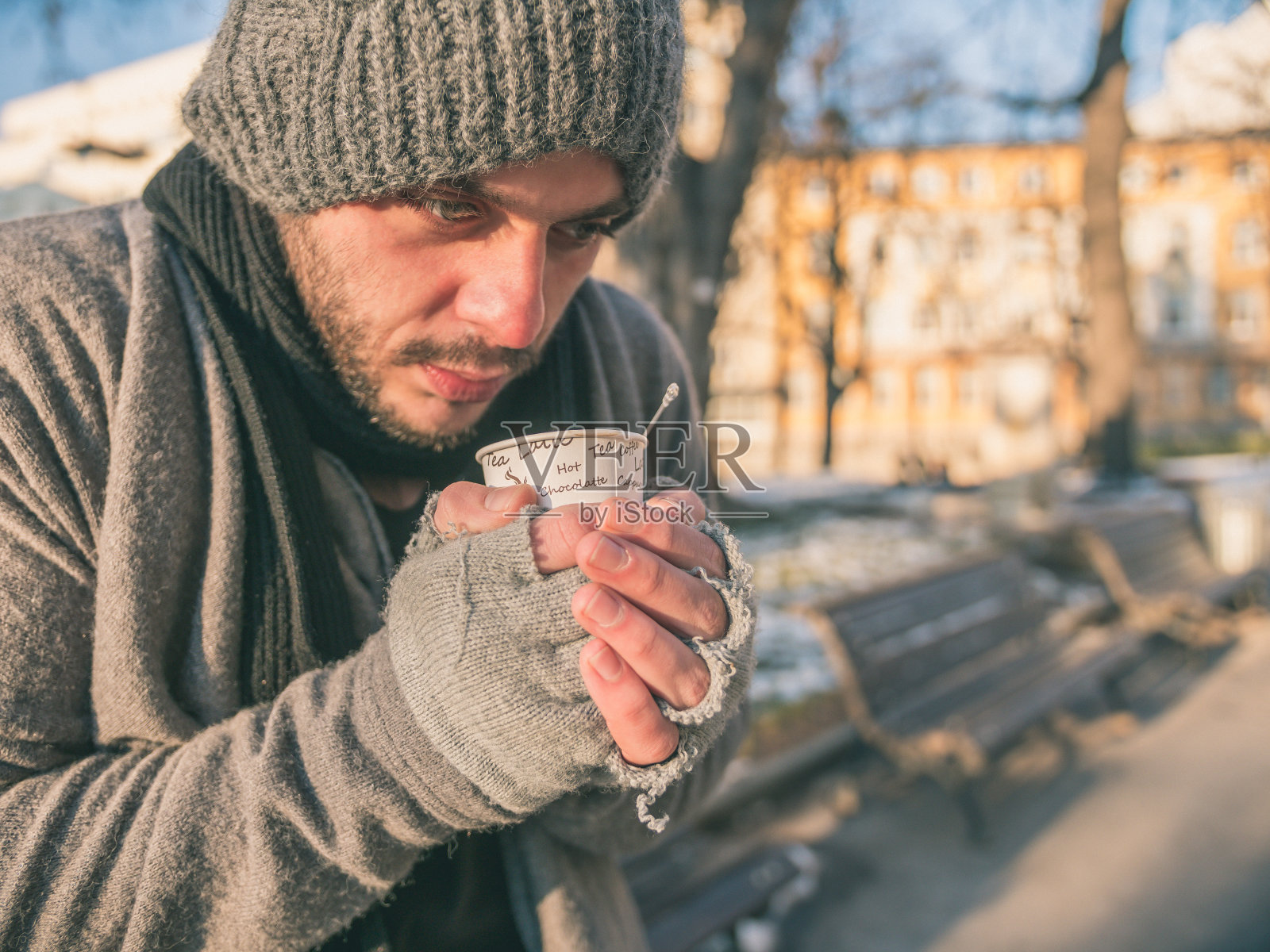 一个穷困潦倒的可怜的年轻人，一个拿着热茶或咖啡的乞丐照片摄影图片