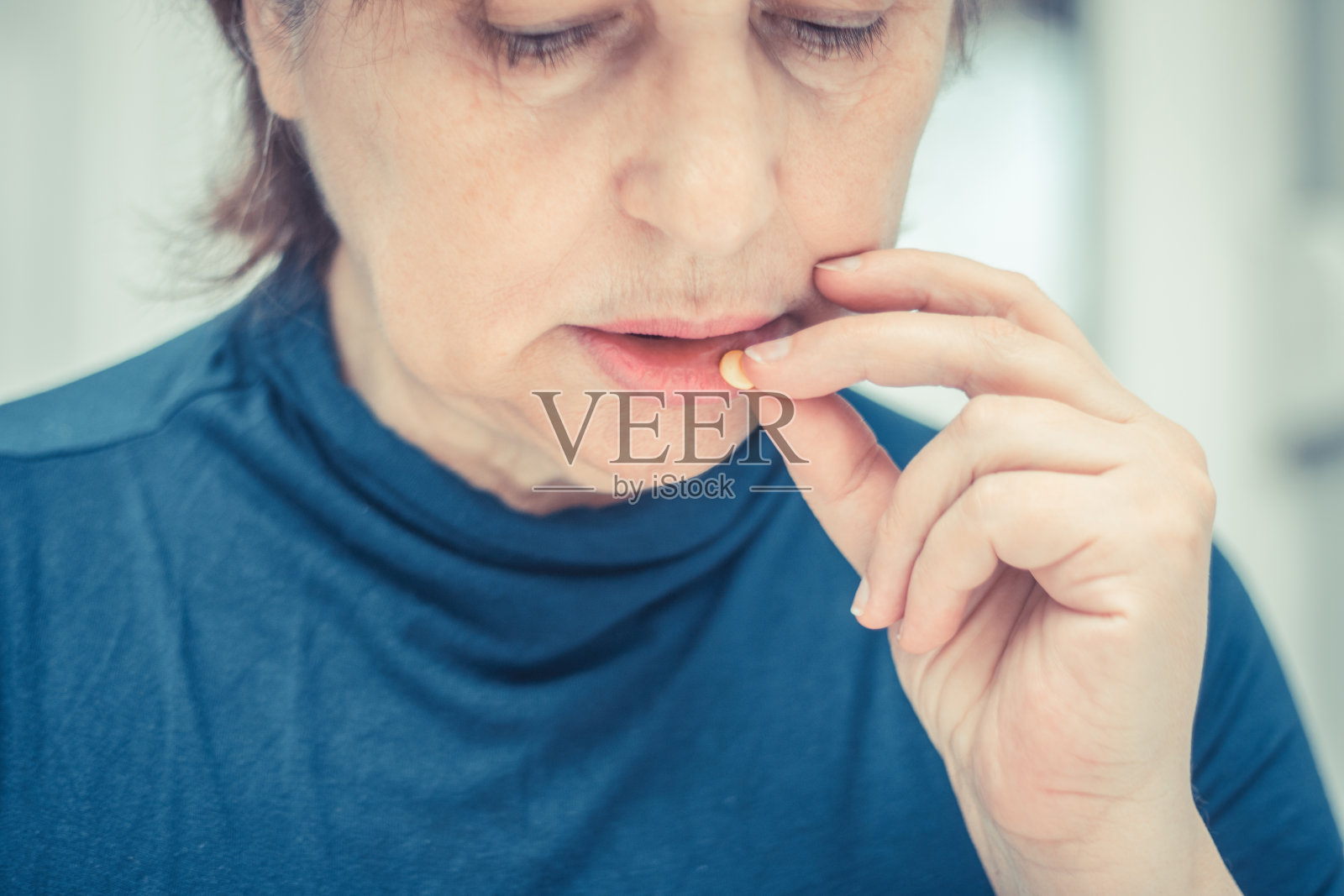 悲伤成熟的女人吃药的特写。照片摄影图片