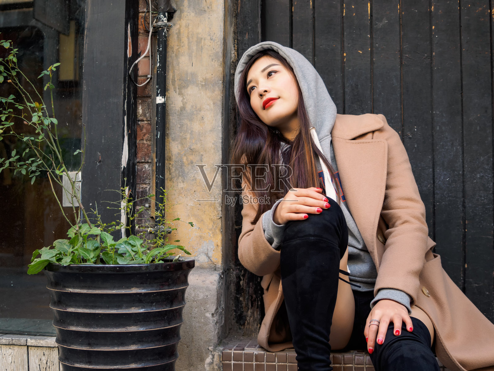 一个性感的中国年轻女孩坐在上海新天地的木门旁的肖像。照片摄影图片