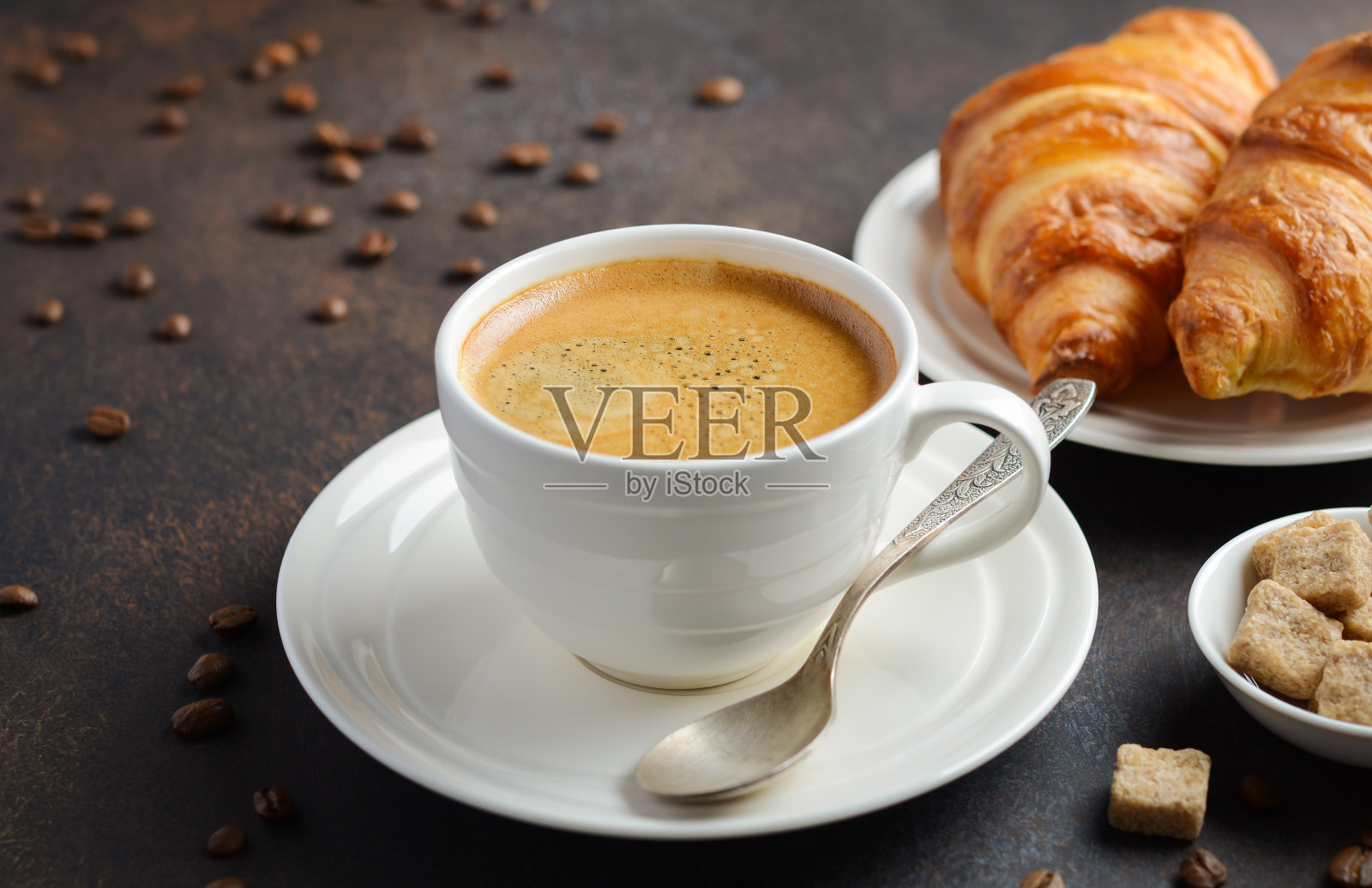 一杯新鲜的咖啡和牛角面包在深色的背景。照片摄影图片