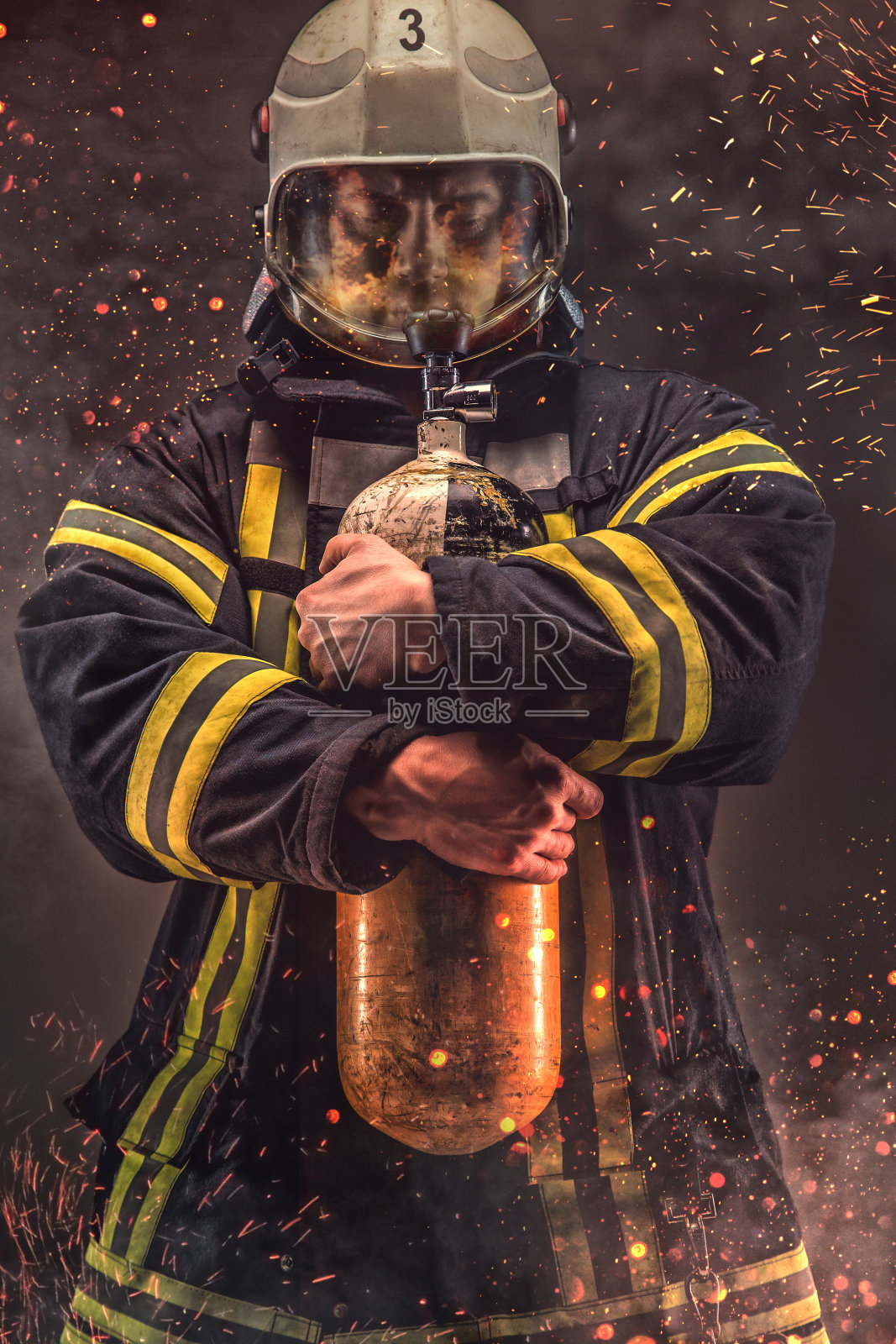 戴着头盔和面罩的消防员手持氧气罐。照片摄影图片