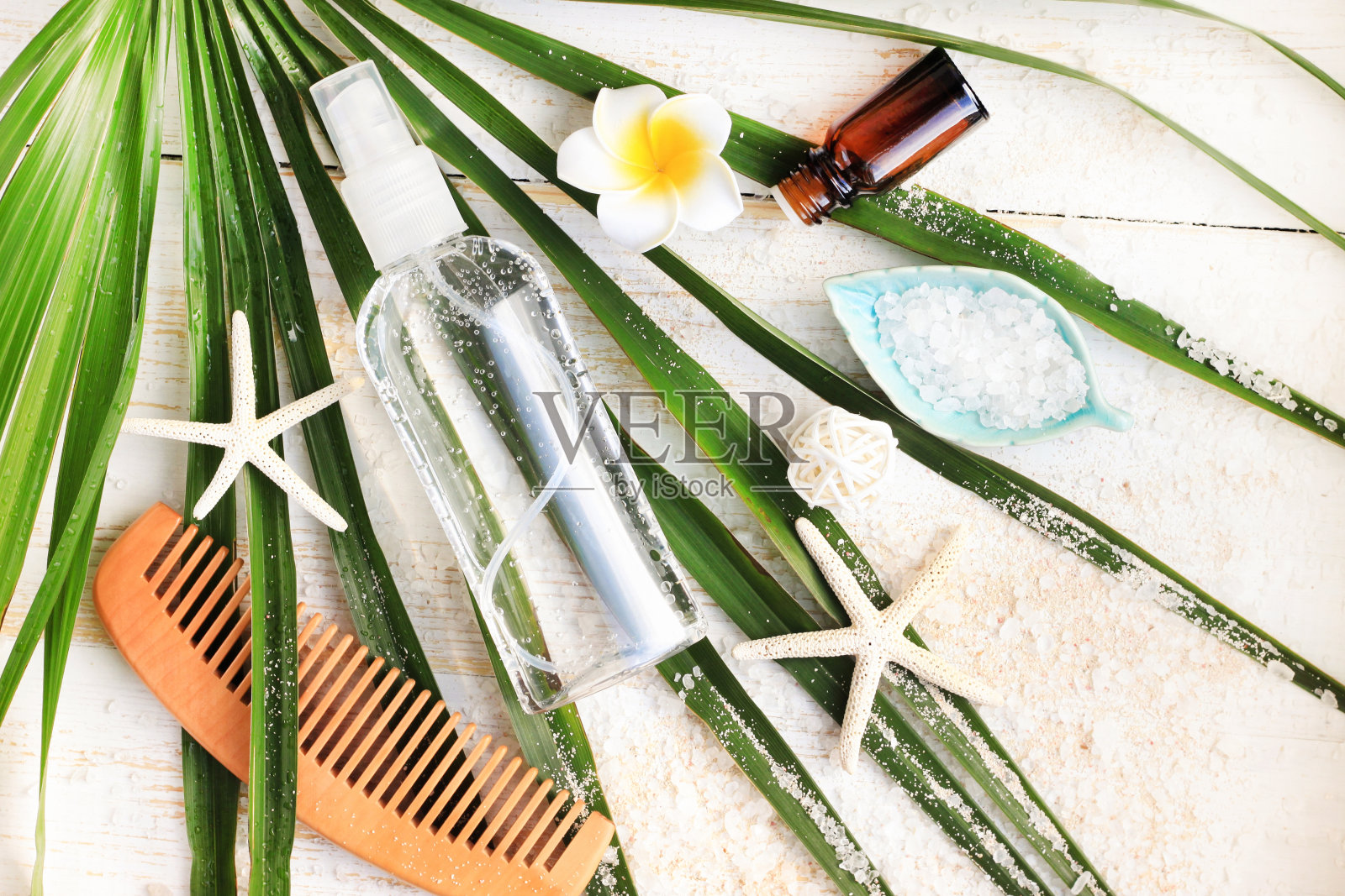 夏日美容护理套装。一瓶矿物海盐头发和身体喷雾从绿色棕榈叶上俯瞰照片摄影图片