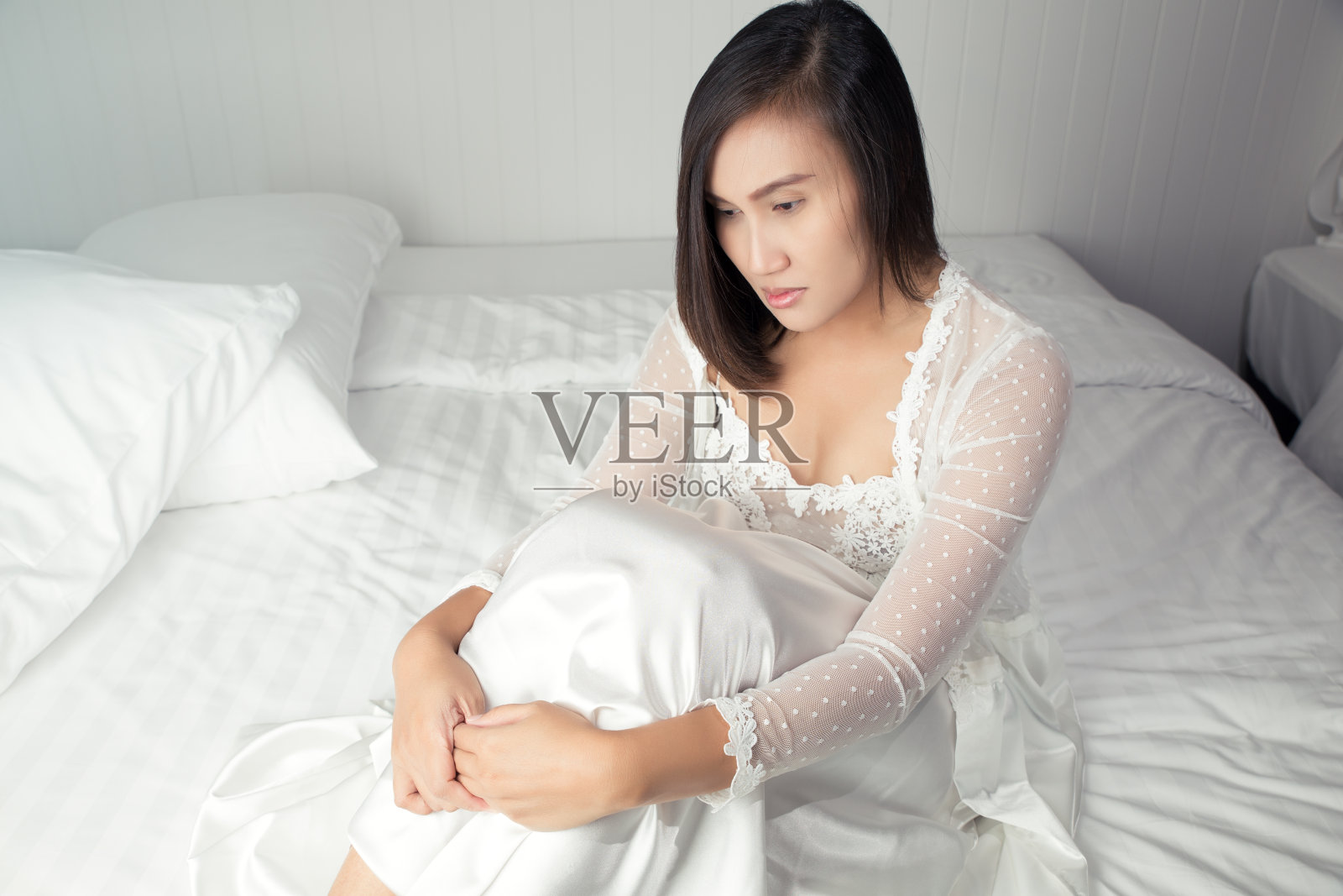 亚洲女人在白色的缎子睡衣躺在床上遭受抑郁症，没有睡觉，女士因为太早醒来压力大，悲伤的抑郁症的人遭受失眠照片摄影图片