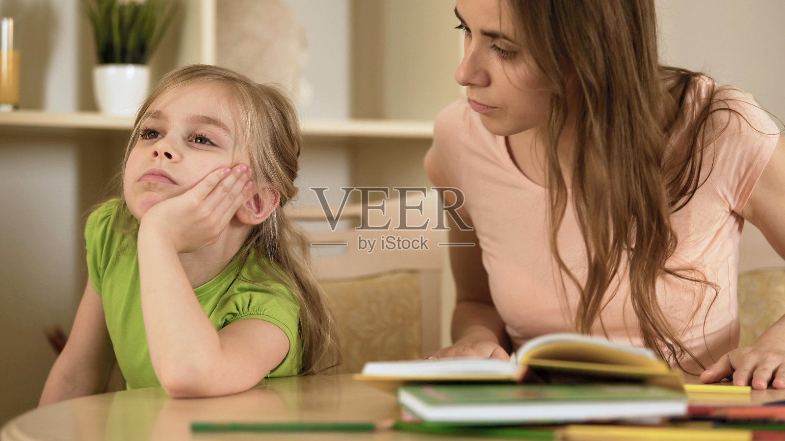 心烦意乱的妈妈不耐烦的让女儿做作业，在家自学照片摄影图片