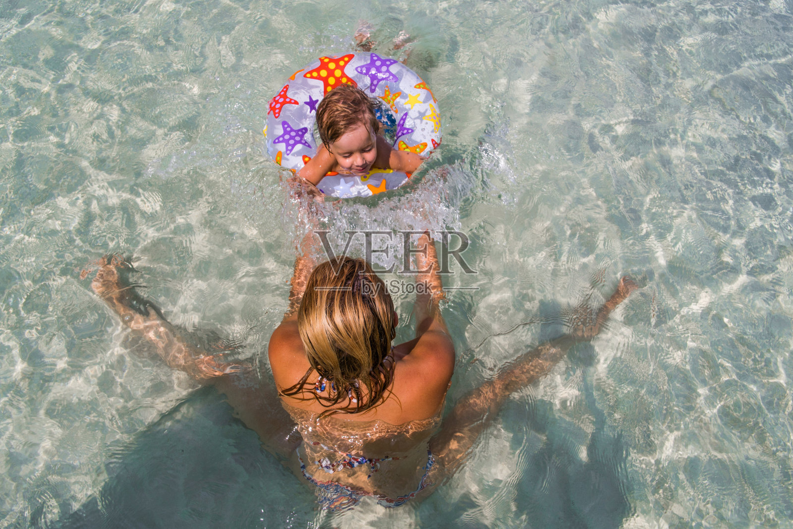 高角度的观点，一个母亲有乐趣与她的小儿子在海里。照片摄影图片