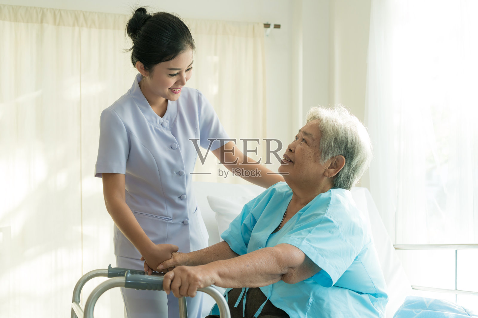 亚洲年轻护士支持老年病人残疾妇女在医院使用助行器。老年病人的护理理念。照片摄影图片