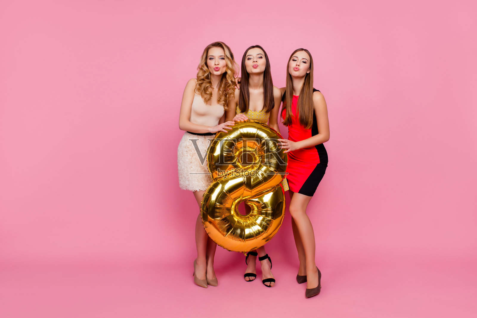 全身像的三个漂亮，有趣的女孩，飞吻相机，庆祝，妇女节，八点钟，有金色的气球，站在粉红色的背景照片摄影图片