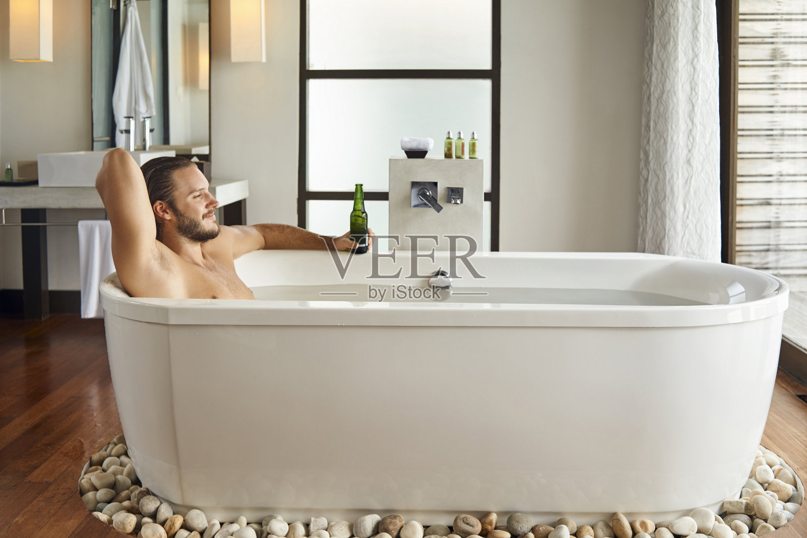 年轻英俊的男人享受在浴缸里喝啤酒照片摄影图片