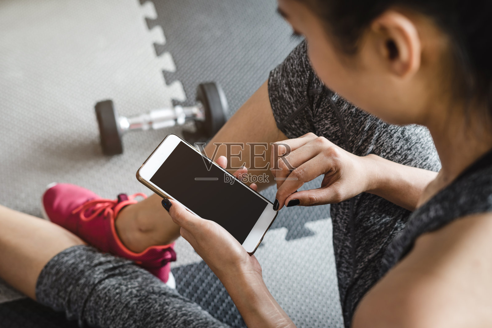年轻的亚洲女性在健身房使用智能手机照片摄影图片