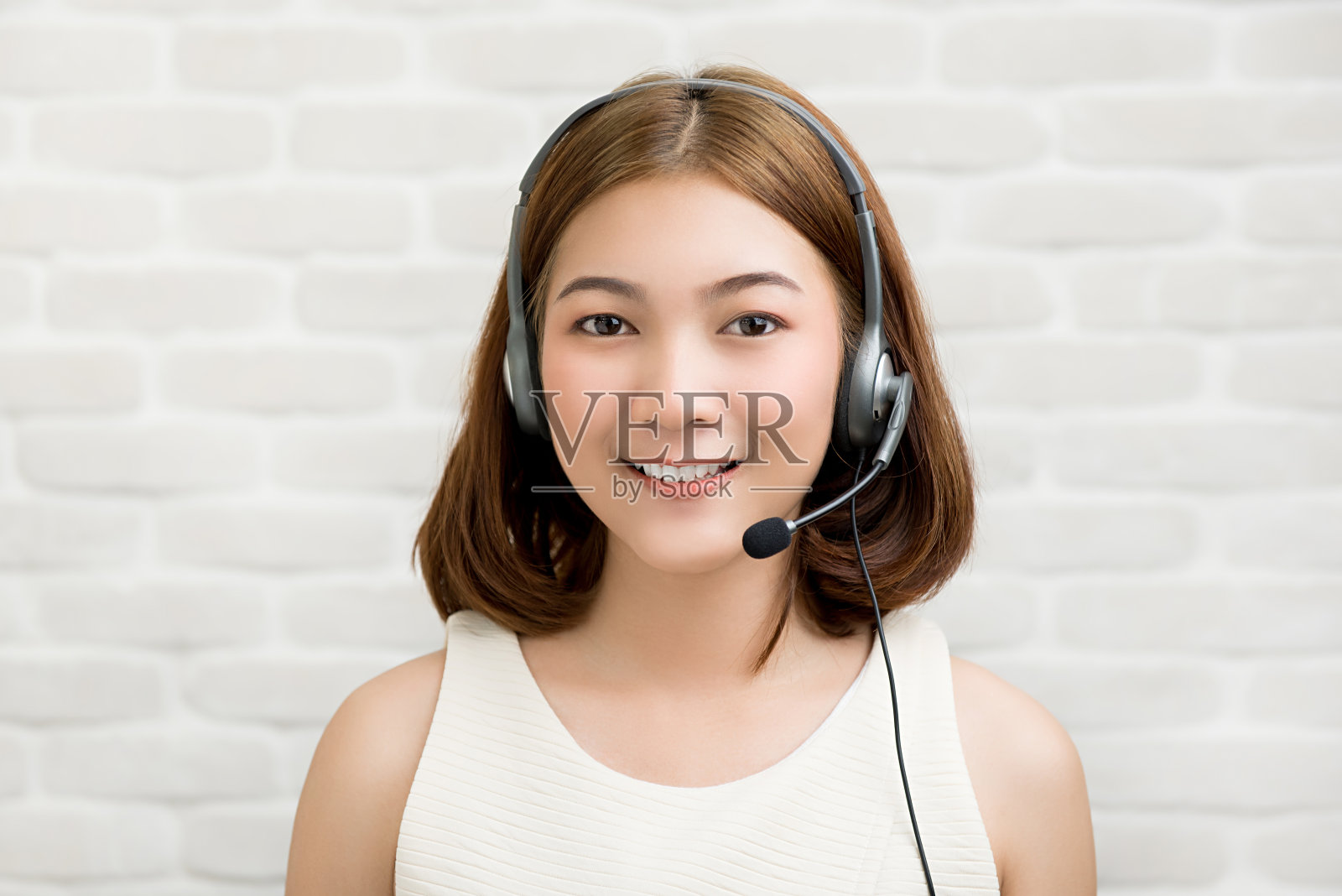 随意的亚洲女商人戴着麦克风耳机作为电话销售客户服务代理人照片摄影图片