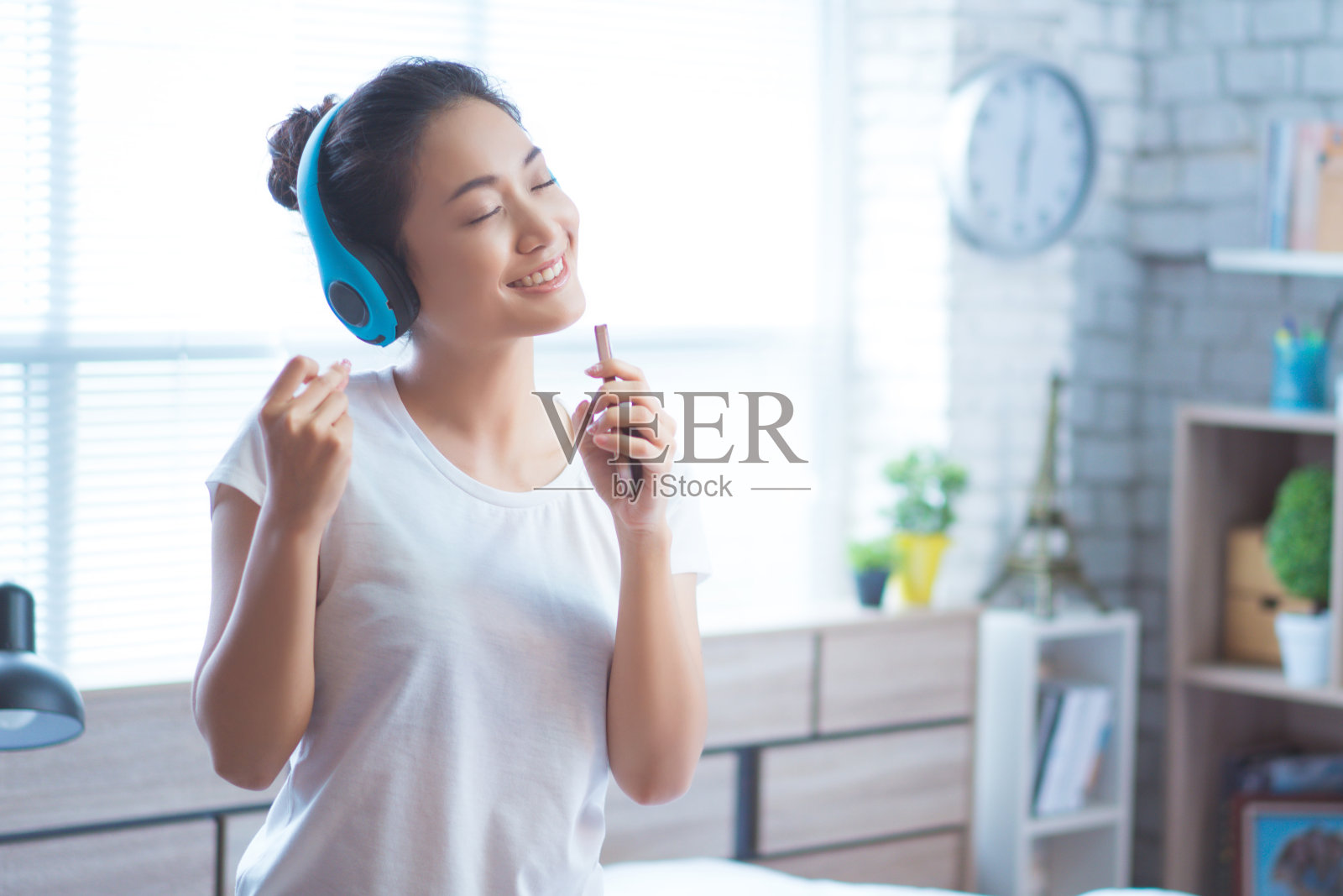 亚洲妇女正在听音乐，她在房间里唱歌。幸福的照片摄影图片