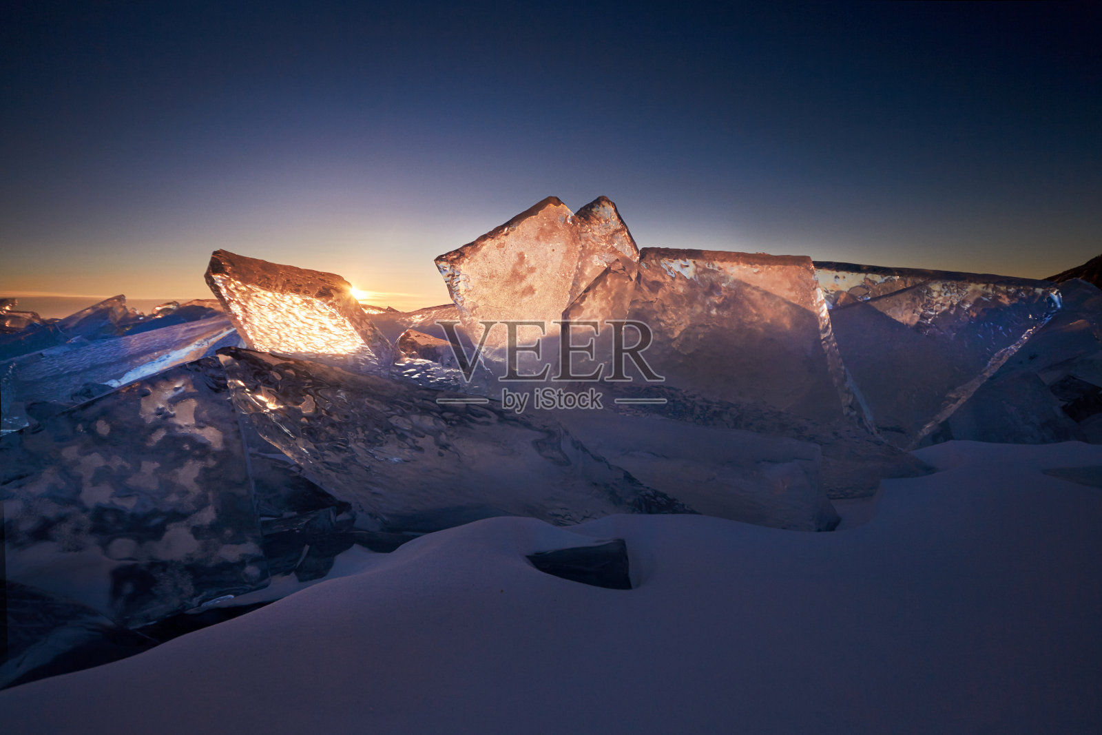 日落时分，贝加尔湖上的一切都被冰雪覆盖着，厚厚的透明的蓝色冰。夕阳下的贝加尔湖。令人惊叹的地方，联合国教科文组织世界遗产照片摄影图片