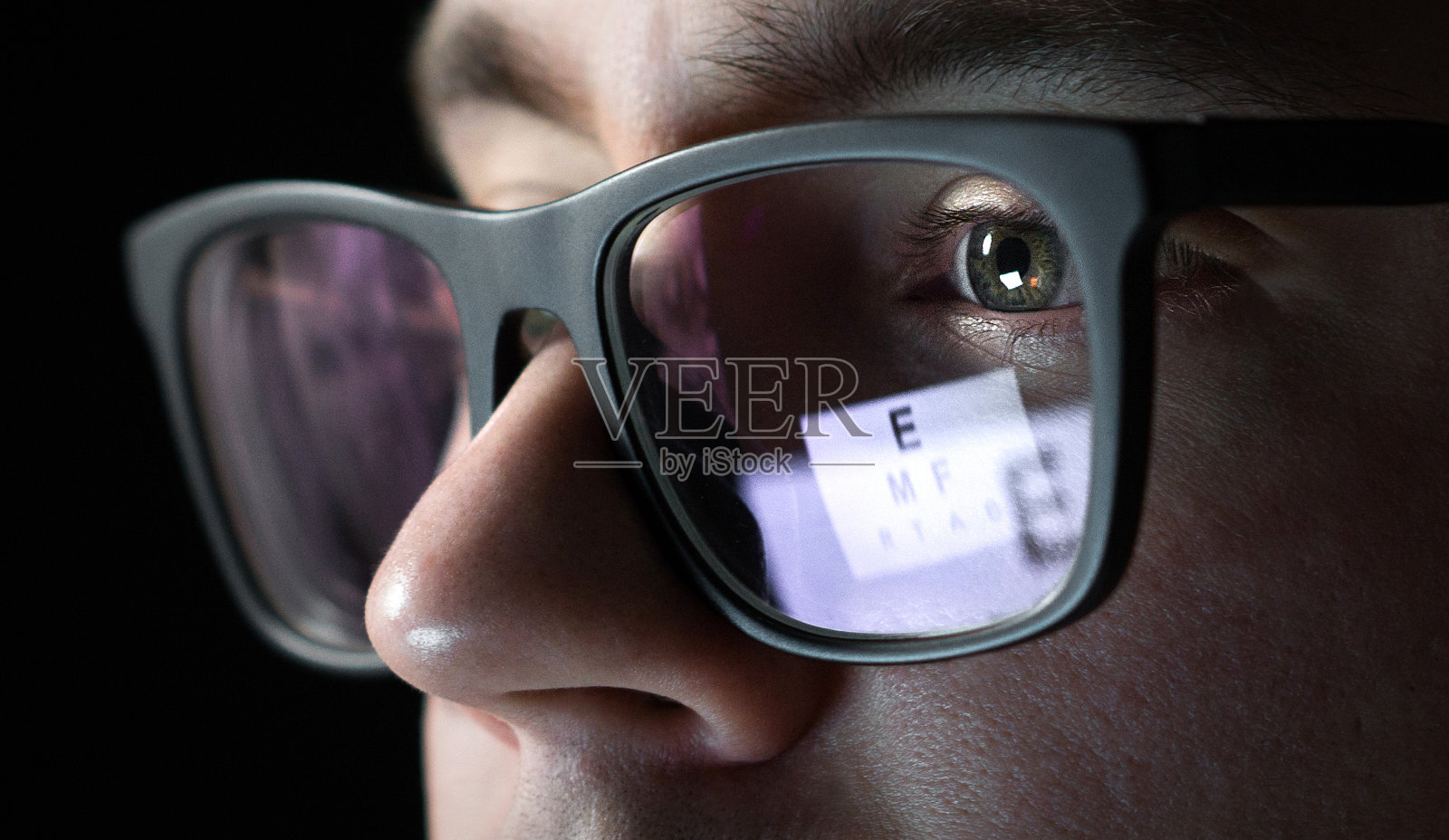 视力检查和检查概念。近距离的人与眼镜在眼镜商测试视力和视力。视力检查。字母表在眼镜上的反射。照片摄影图片