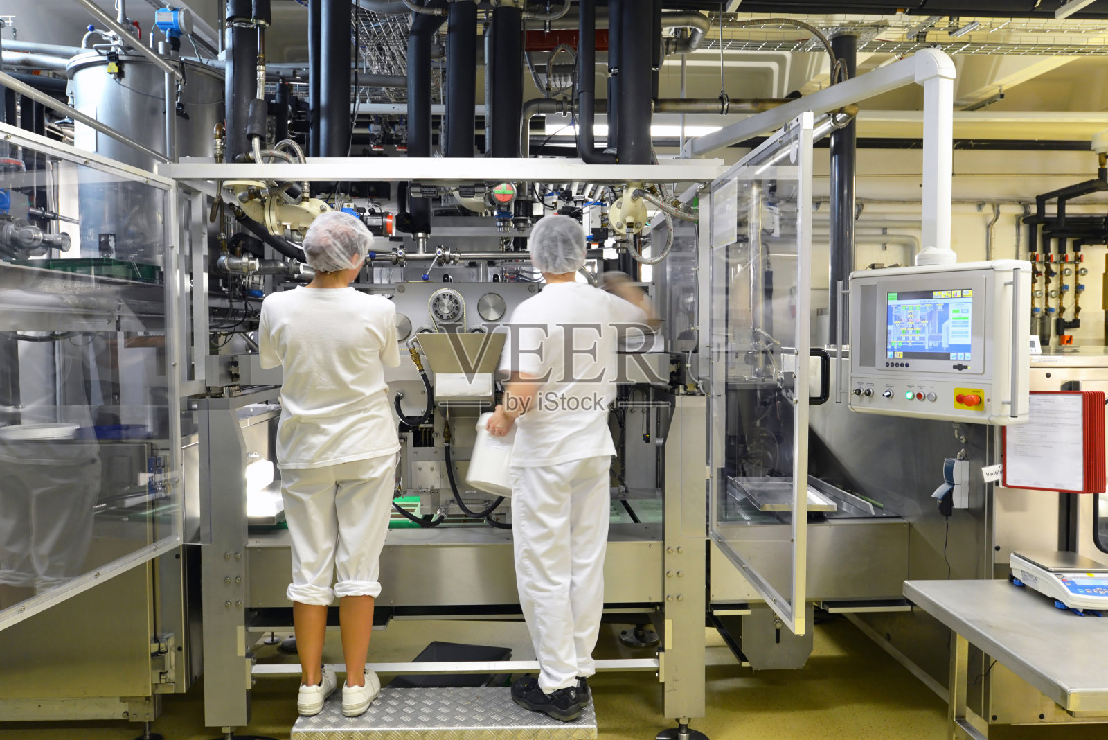 在一家工厂为食品工业生产果仁糖-传送带工人与巧克力照片摄影图片