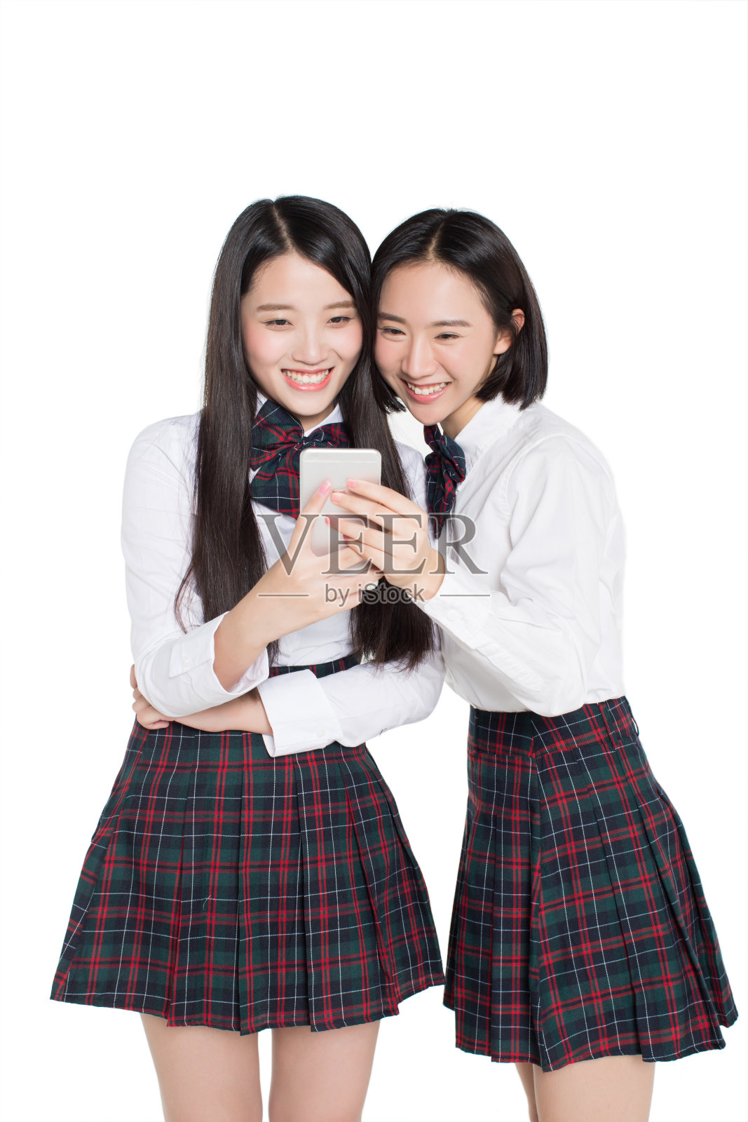 两个快乐的少女看着白色背景下的智能手机照片摄影图片