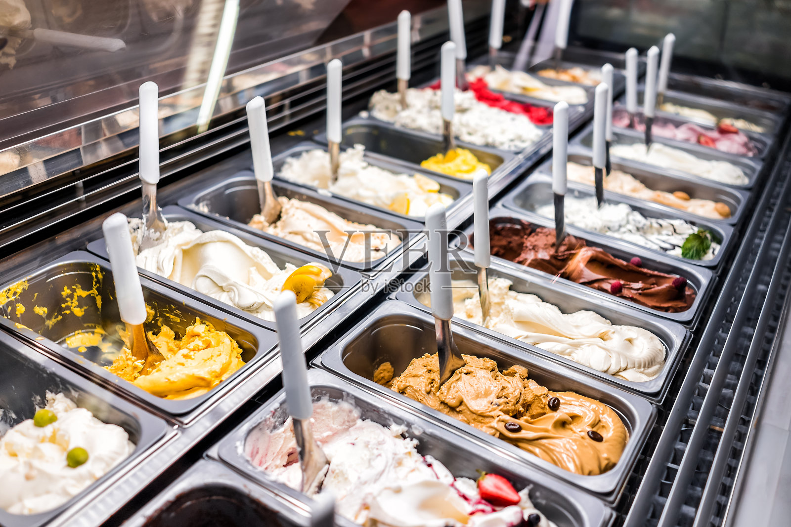 冰淇淋冻酸奶五颜六色的服务柜台客厅与许多勺子口味，冰沙，巧克力，浇头，咖啡照片摄影图片