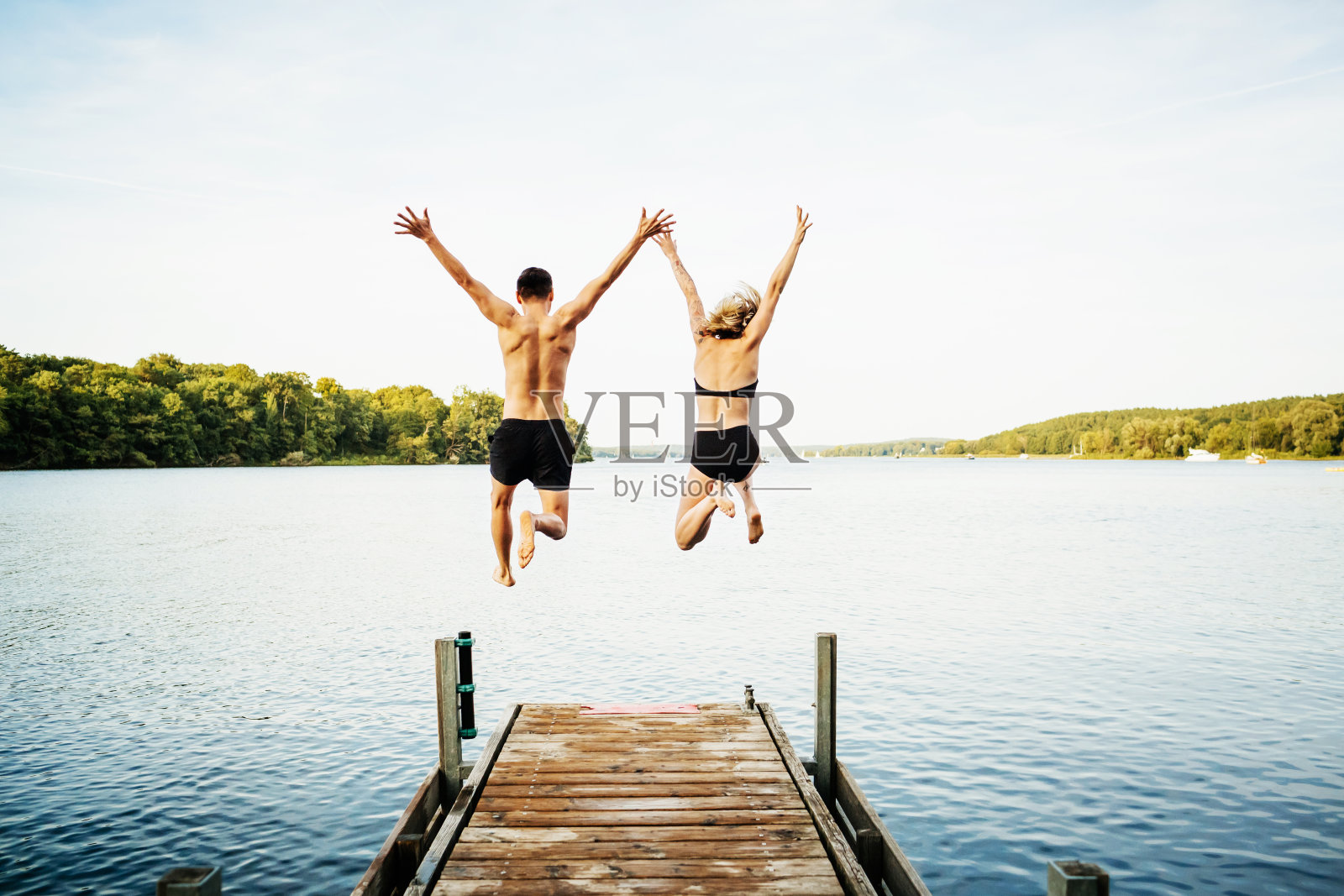 两个朋友一起从码头上跳下去照片摄影图片