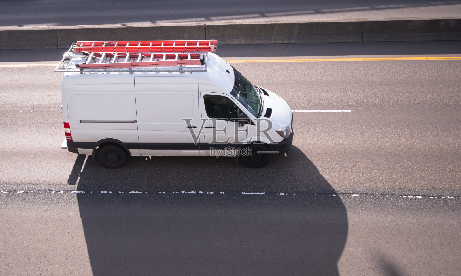商业货运微型货车，车顶有长长的引线，行驶在通往服务点的道路上照片摄影图片
