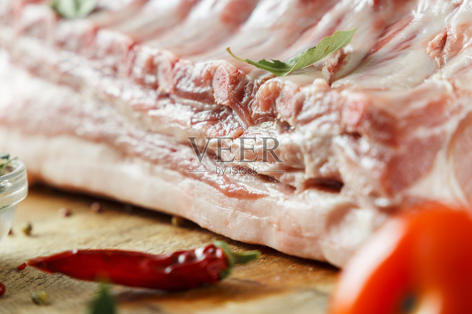 背景的肉。特写-生肉猪肉在一个蓝色的背景与胡椒和香料照片摄影图片