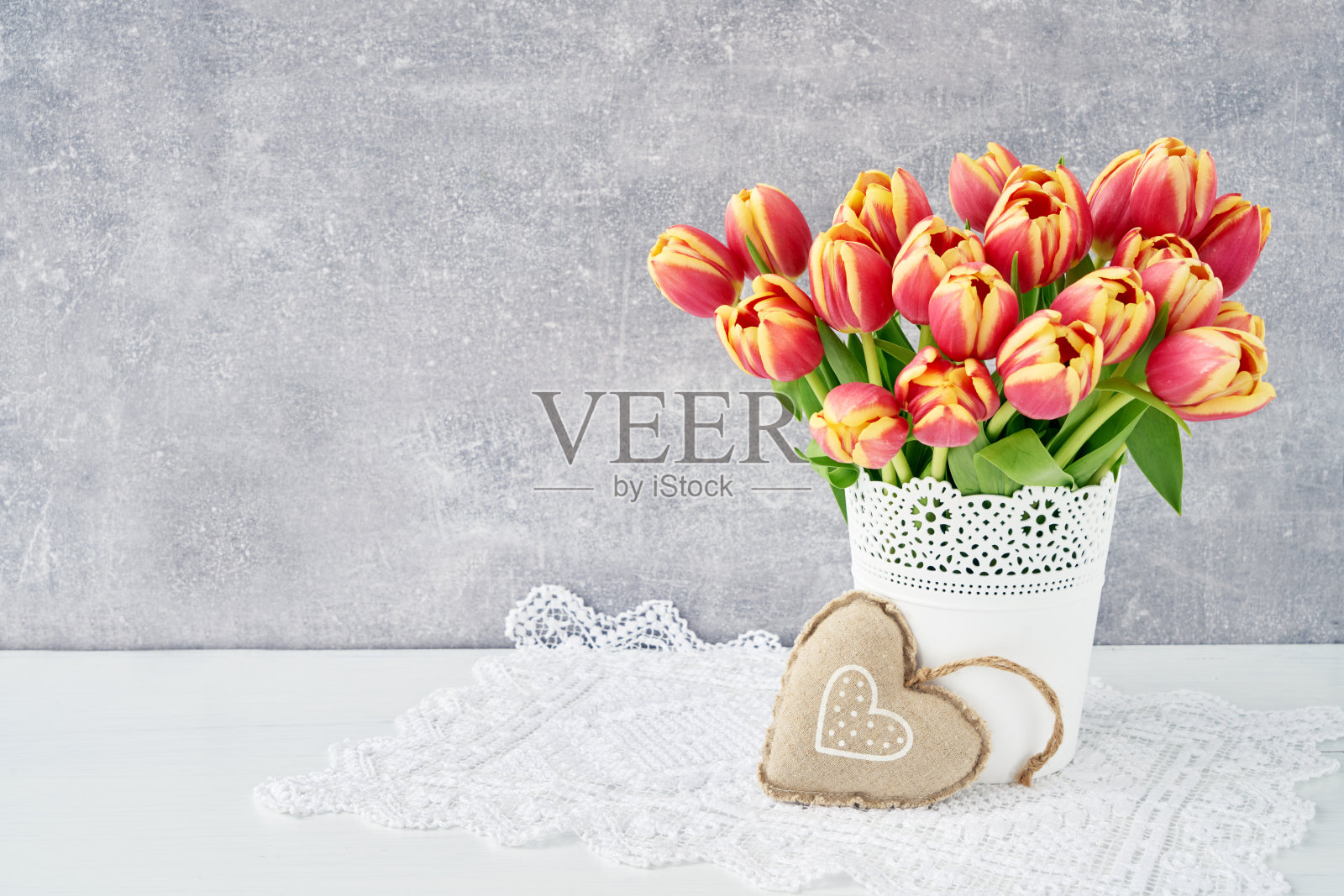 红色郁金香花束，白色花瓶，饰以织心。情人节，母亲节，生日概念。本空间照片摄影图片