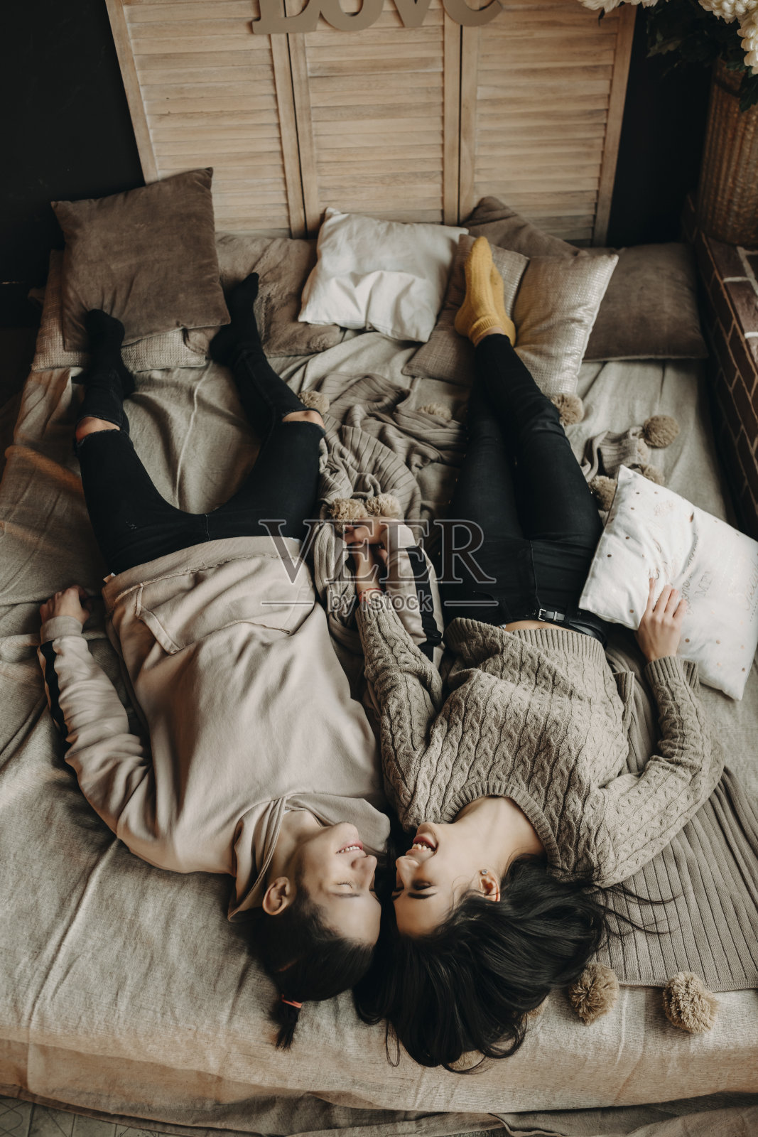 在舒适的房间里，一对美丽的夫妇在床上互相微笑。照片摄影图片
