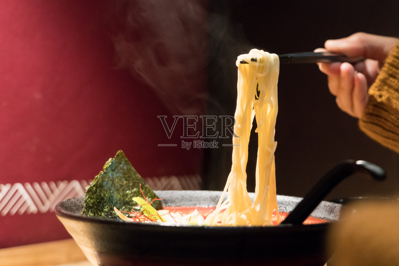 面条拉面用筷子夹住女人的手，食品饮料概念与拷贝空间照片摄影图片