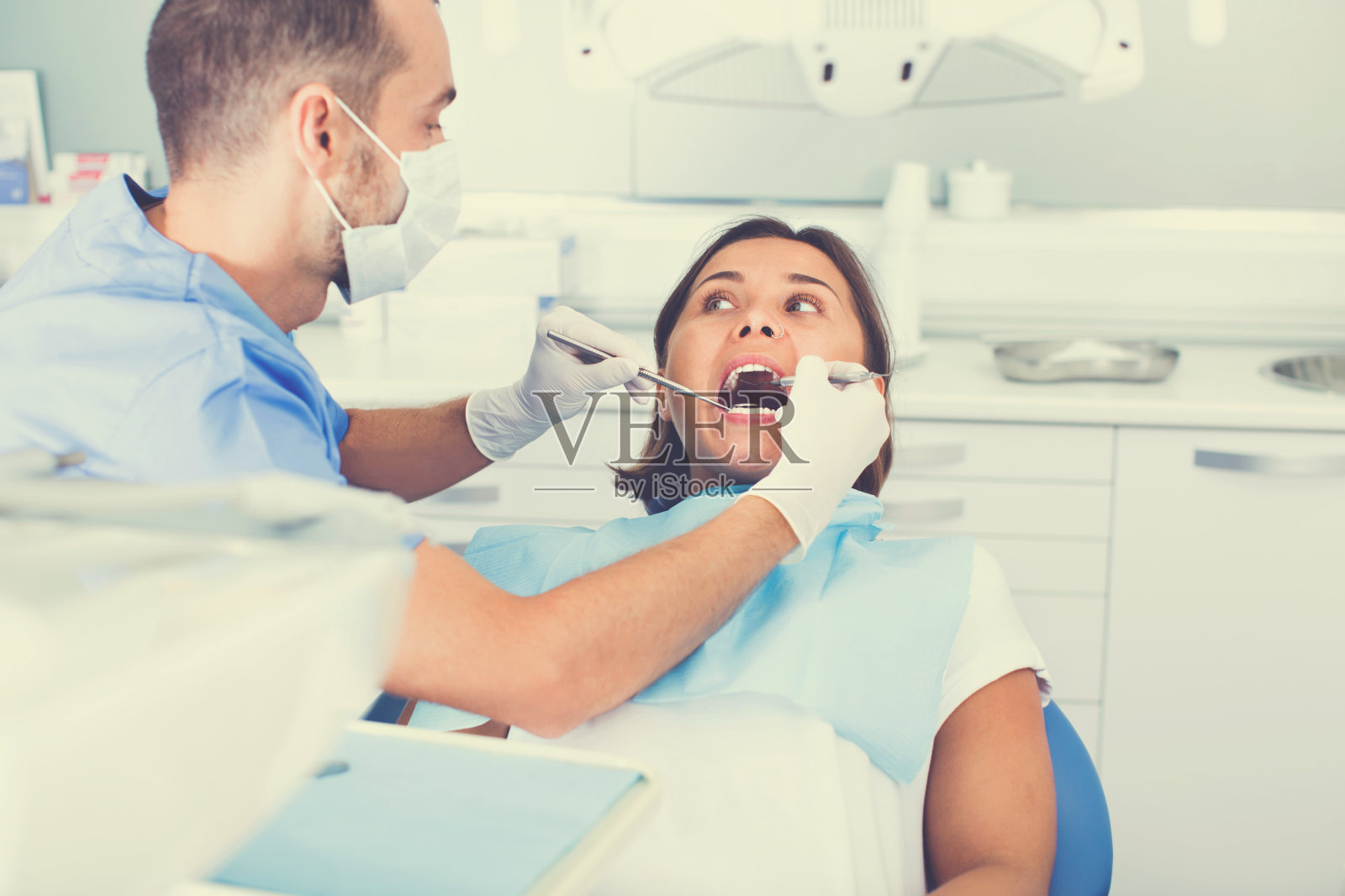 牙医正在治疗一位坐在牙科椅上的女病人照片摄影图片