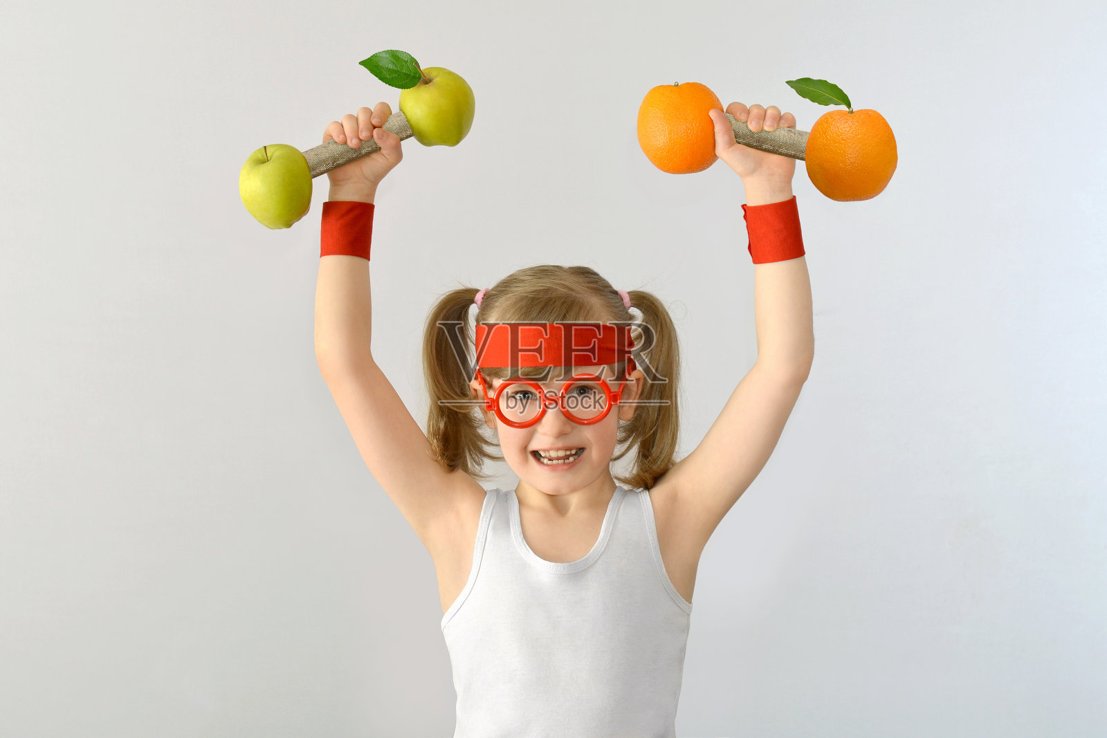 孩子，戴眼镜的孩子举起苹果和橘子的重量。照片摄影图片