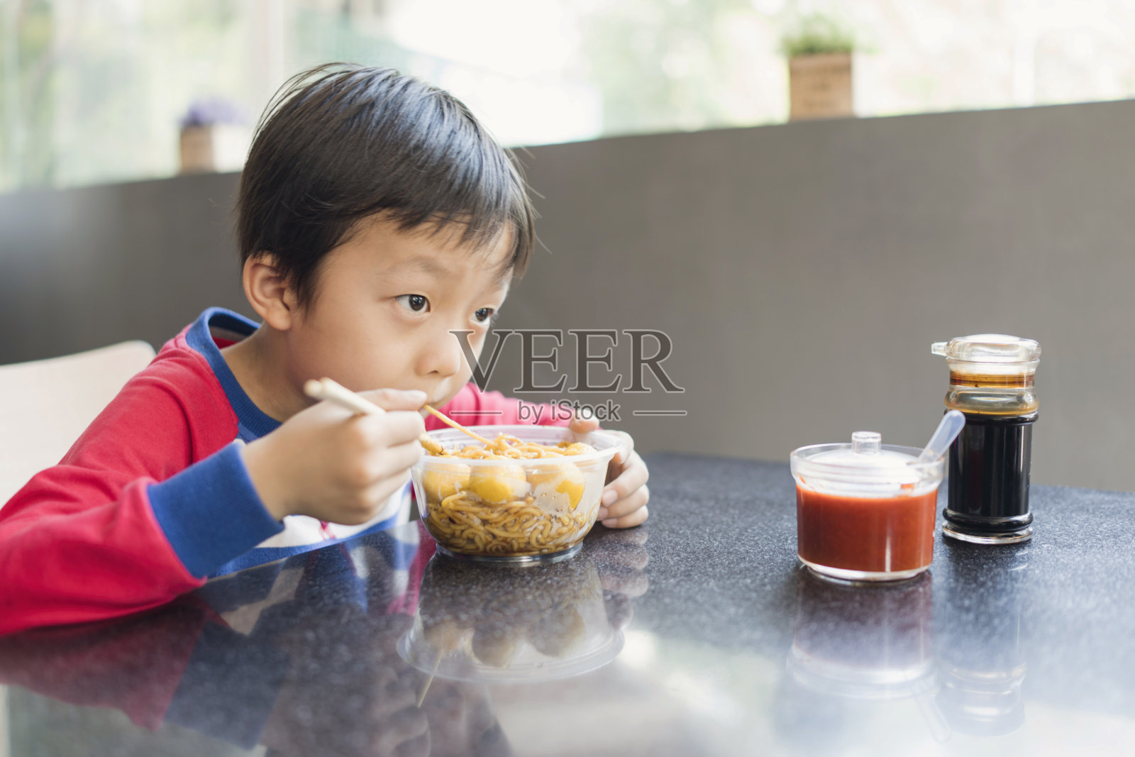 亚洲小孩用筷子吃美味的面条照片摄影图片