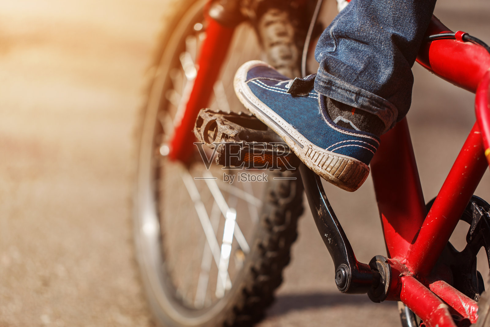 细节儿童骑自行车的脚在户外阳光路骑自行车。踏板和脚的特写照片摄影图片