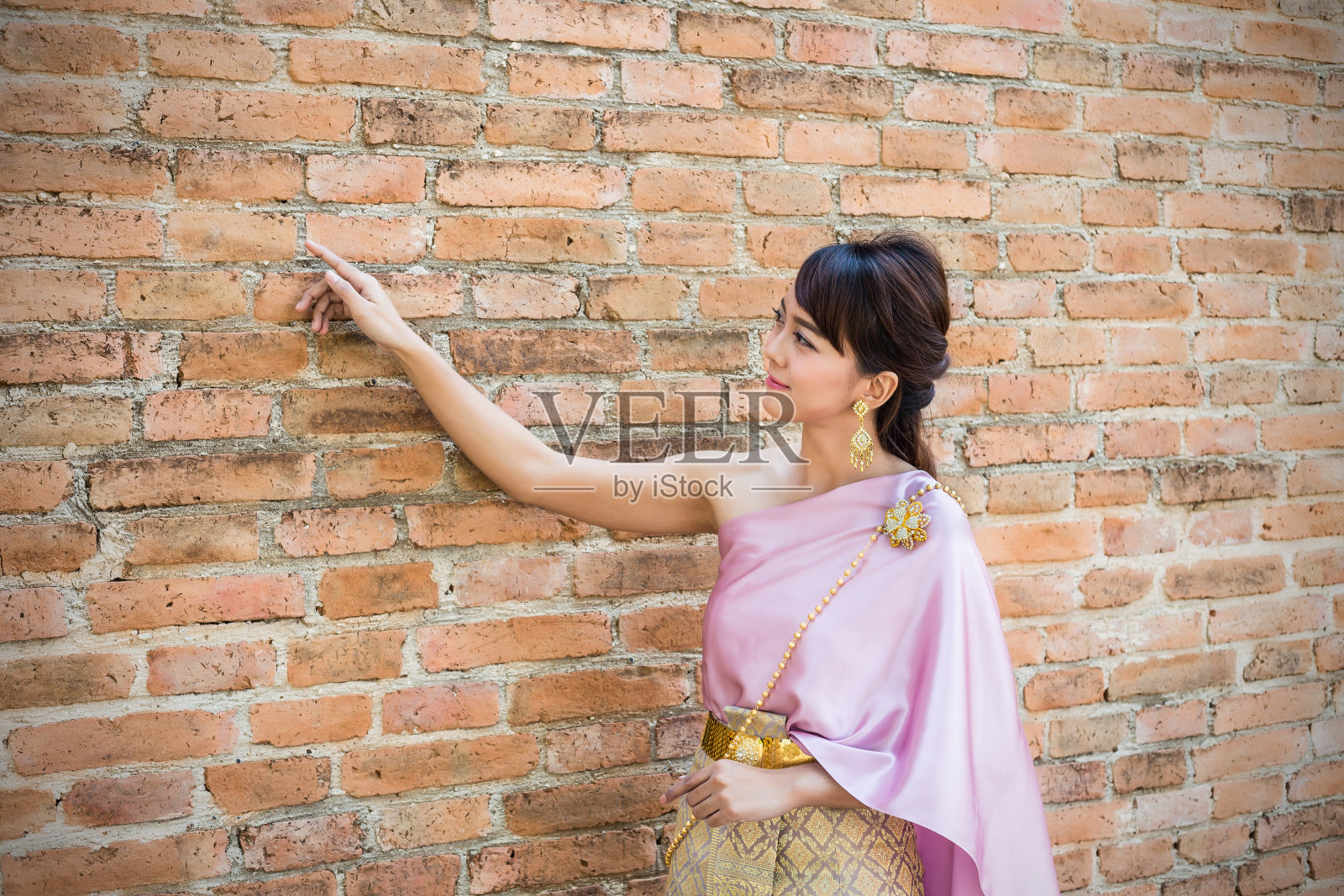 妇女站在那里，穿着泰国传统服装或以古代墙壁为背景的泰国服饰照片摄影图片
