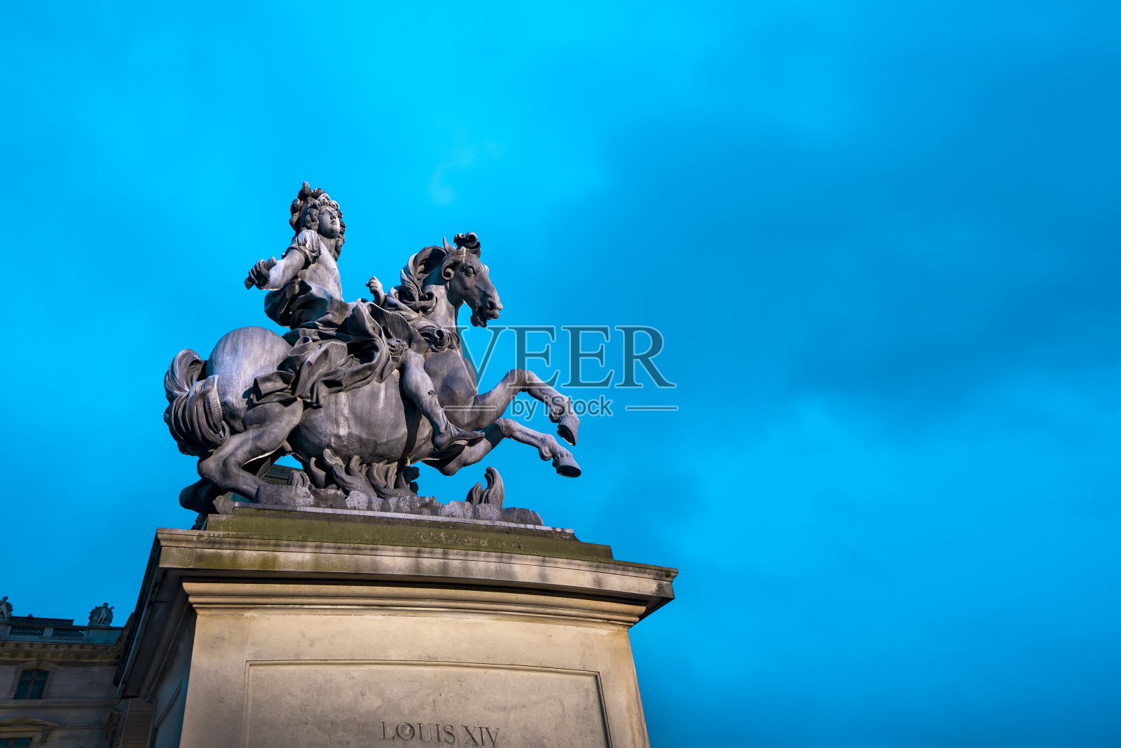 黄昏时分，法国巴黎卢浮宫入口处的路易国王雕像照片摄影图片
