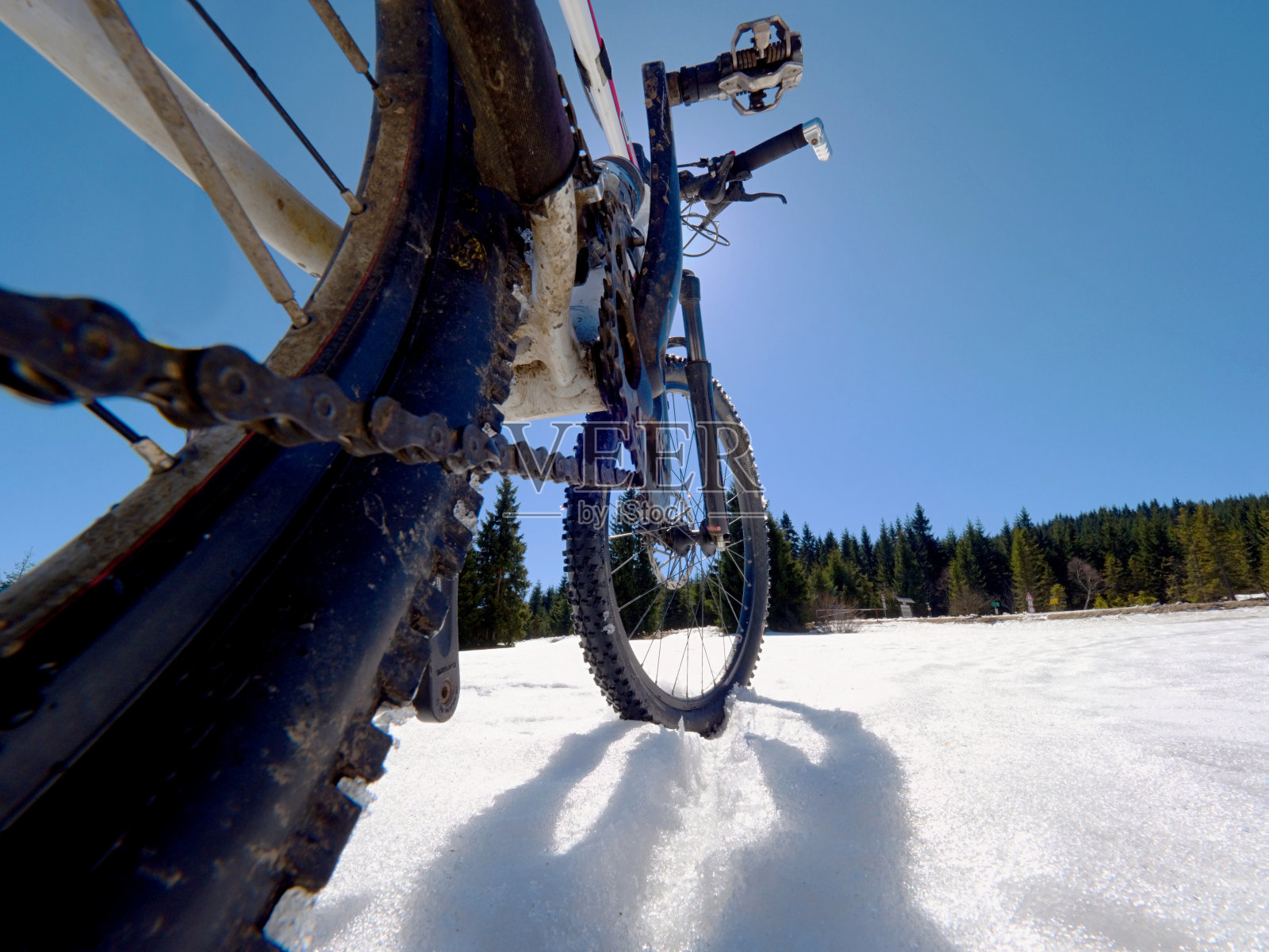 山地车停留在粉末雪中。在厚厚的雪堆中迷路了。雪花在深色轮胎上融化。田野里冬天的天气。照片摄影图片