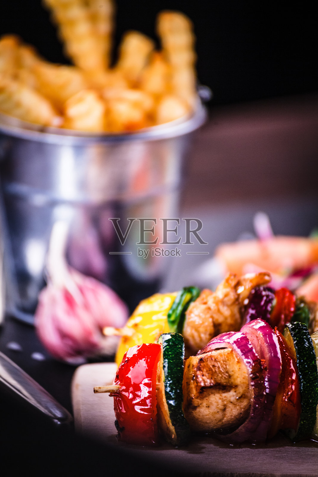 烤肉串——木制背景上的烤肉、薯条和蔬菜照片摄影图片