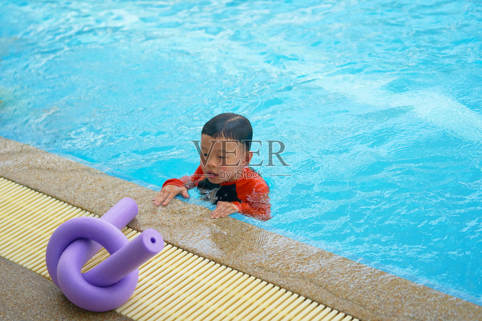 男孩在水池边盯着面条泡沫学游泳照片摄影图片