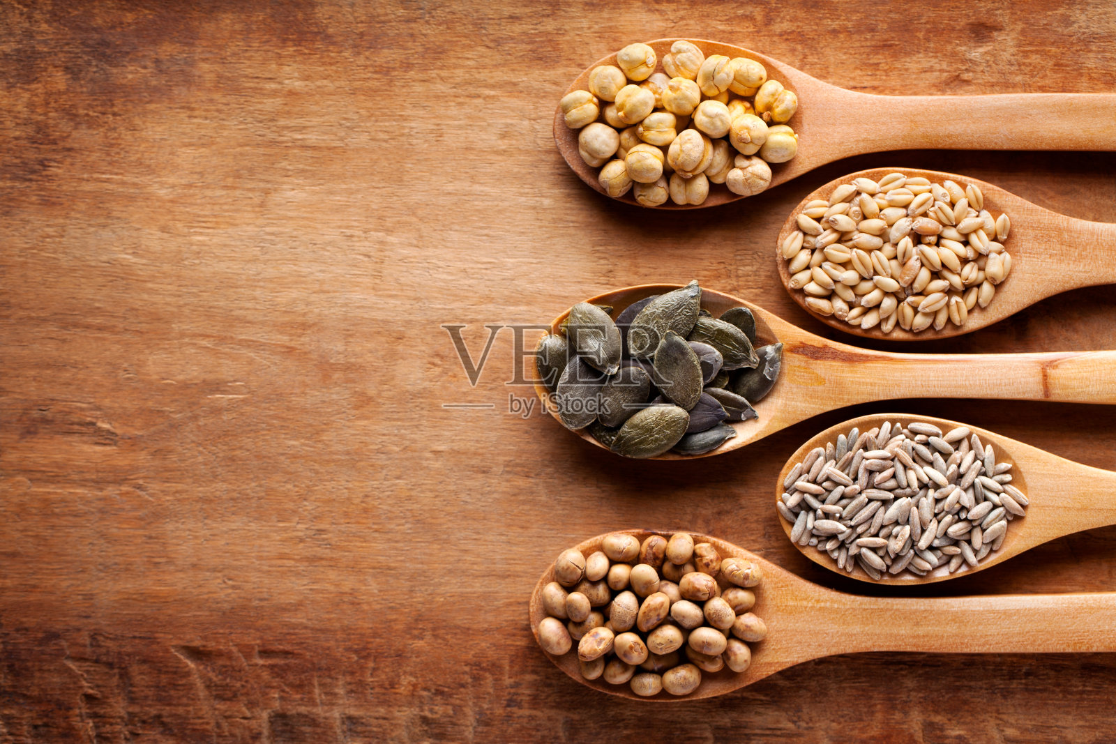 谷物，谷物和种子放在木勺里。燕麦，小麦，黑麦，黑麦，鹰嘴豆，大豆。平的。照片摄影图片