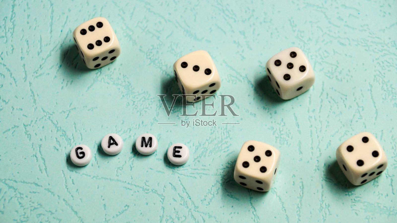 单词“游戏”是由多种颜色的木制字母和游戏骰子在薄荷背景。照片摄影图片