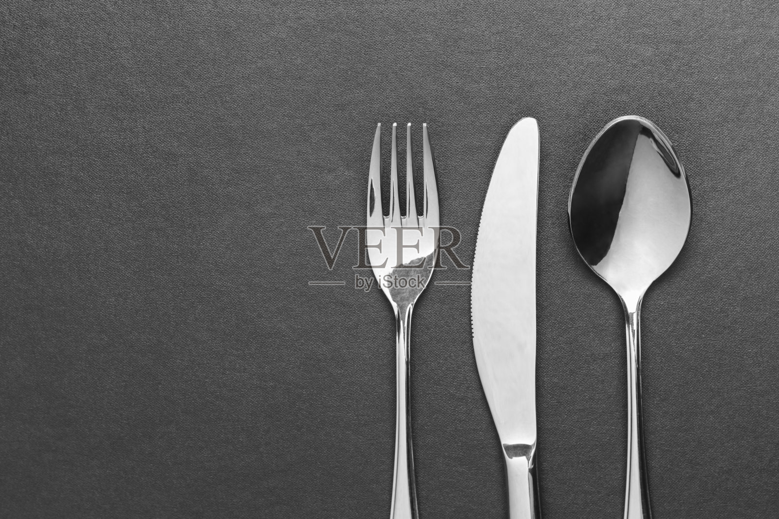刀叉和勺子放在黑色的桌子上，俯视图。照片摄影图片