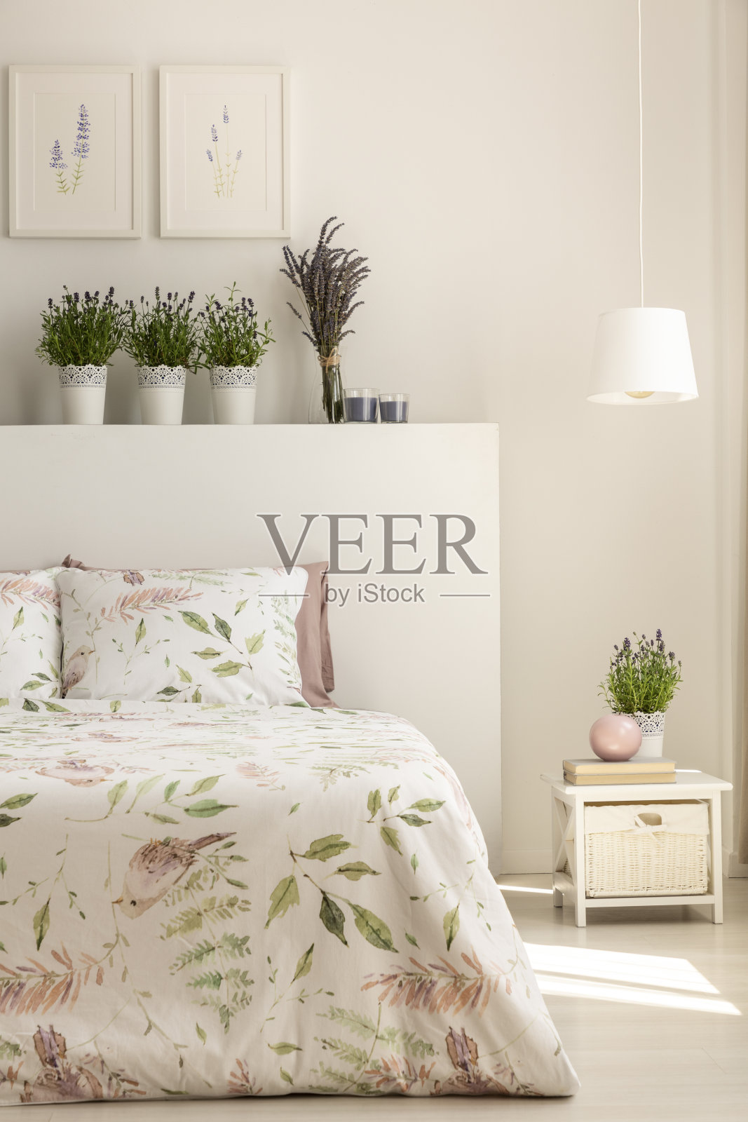 在女性卧室内部，床头板上有植物的床头柜上方的灯。真实的照片照片摄影图片